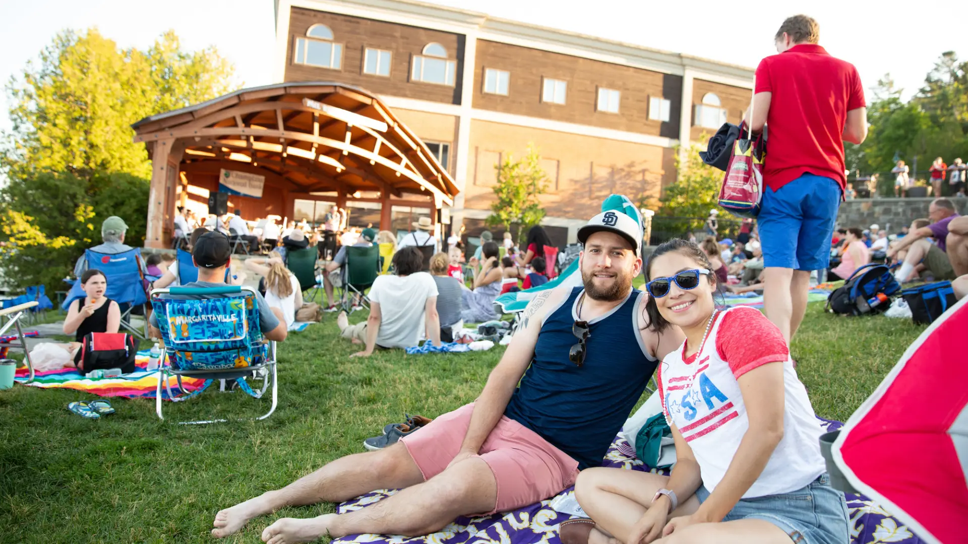 A couple lounges on a blanket in Mid's Park wearing red white and blue