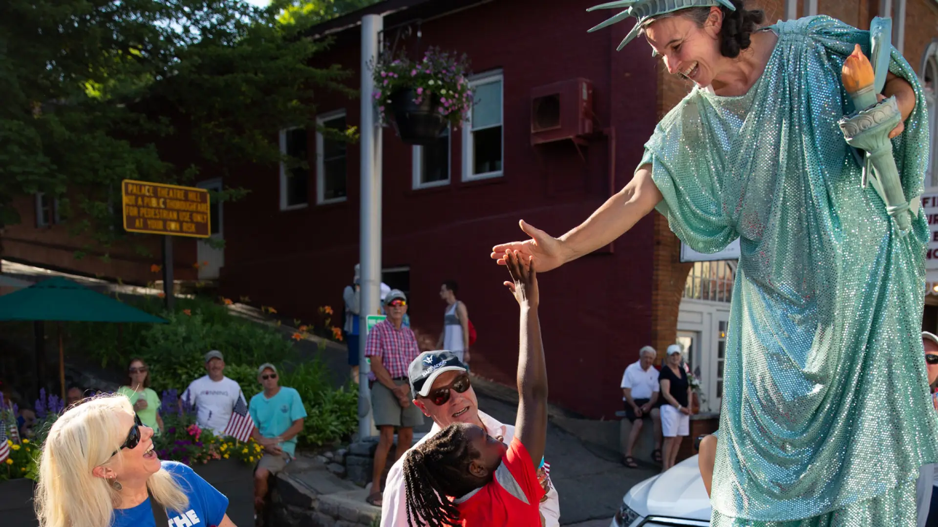 Girl reaches up the give a high five to a women dressed as the Statue of Liberty in the Lake Placid July 4th Parade