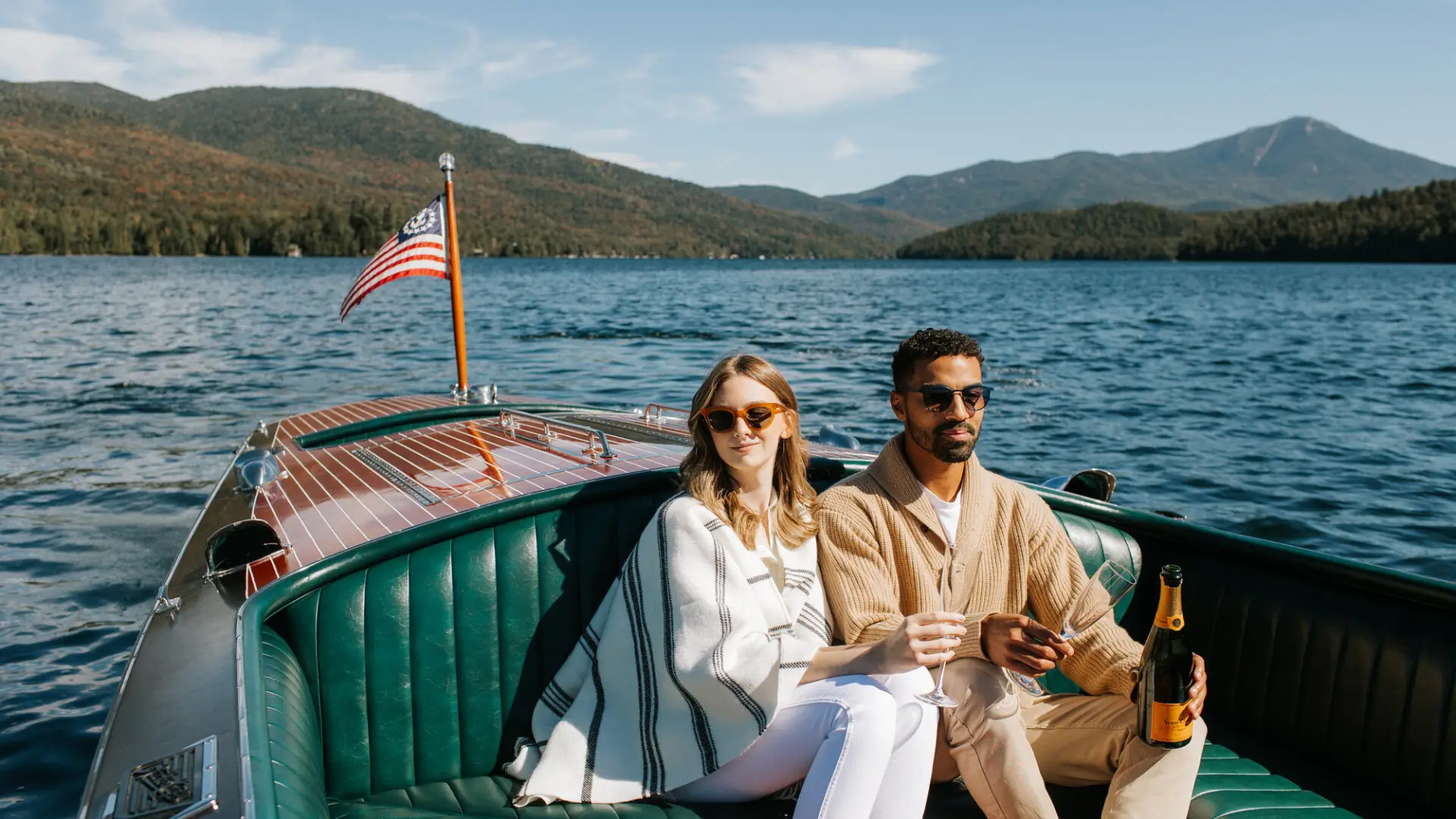 A man and a woman ride in a Chris Craft boat.