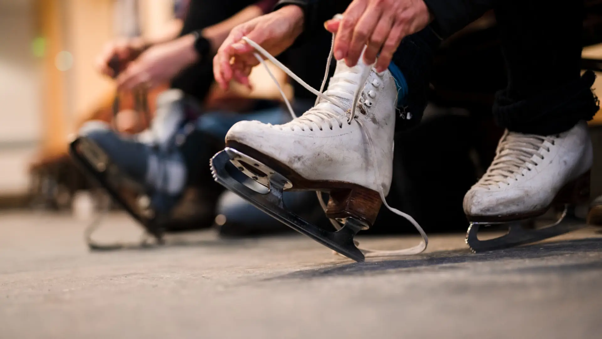 A woman laces ice skates. 