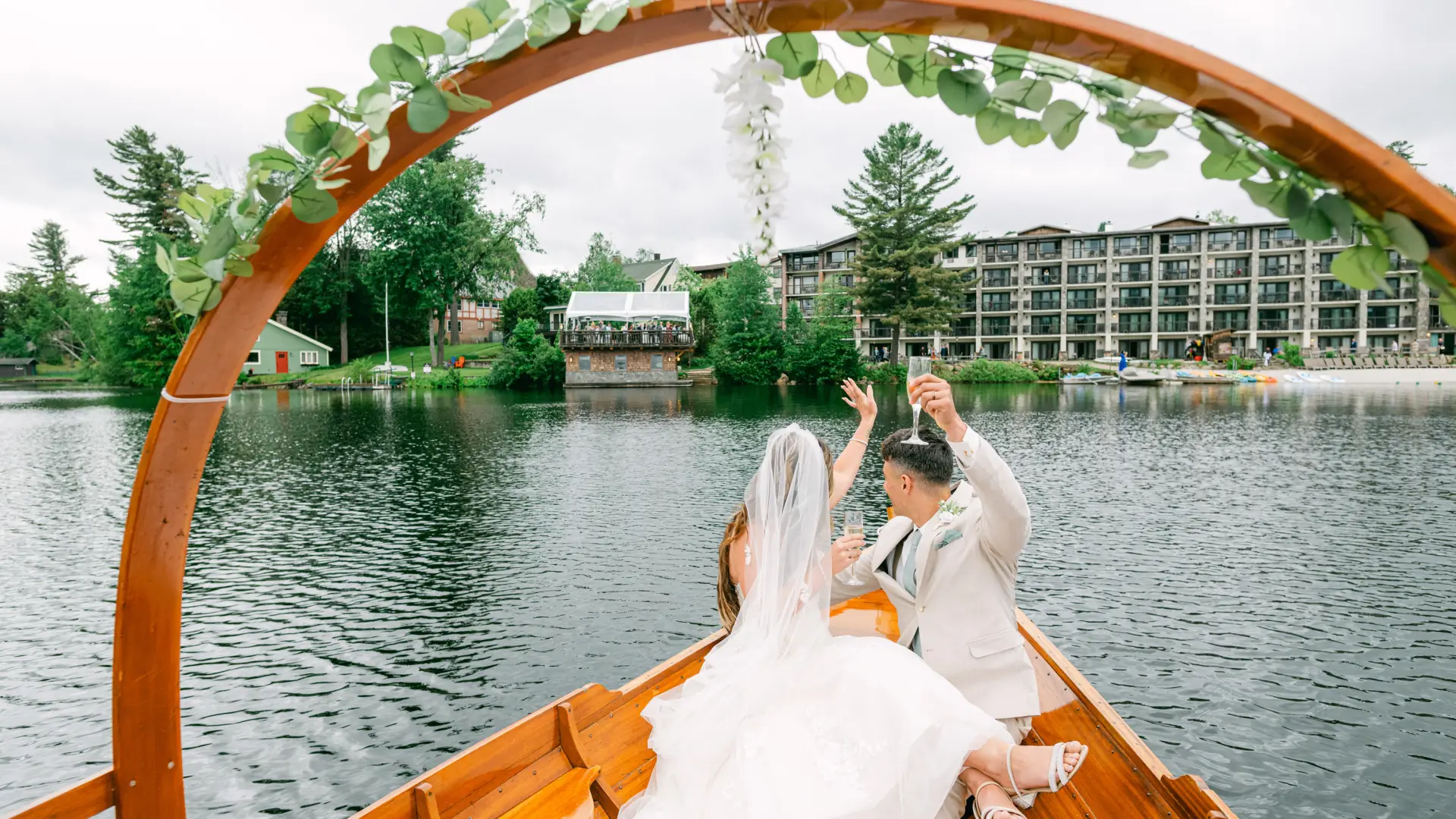 A bride and groom wave at their friends and family at the Golden Arrow during their private gondola ride on Mirror Lake