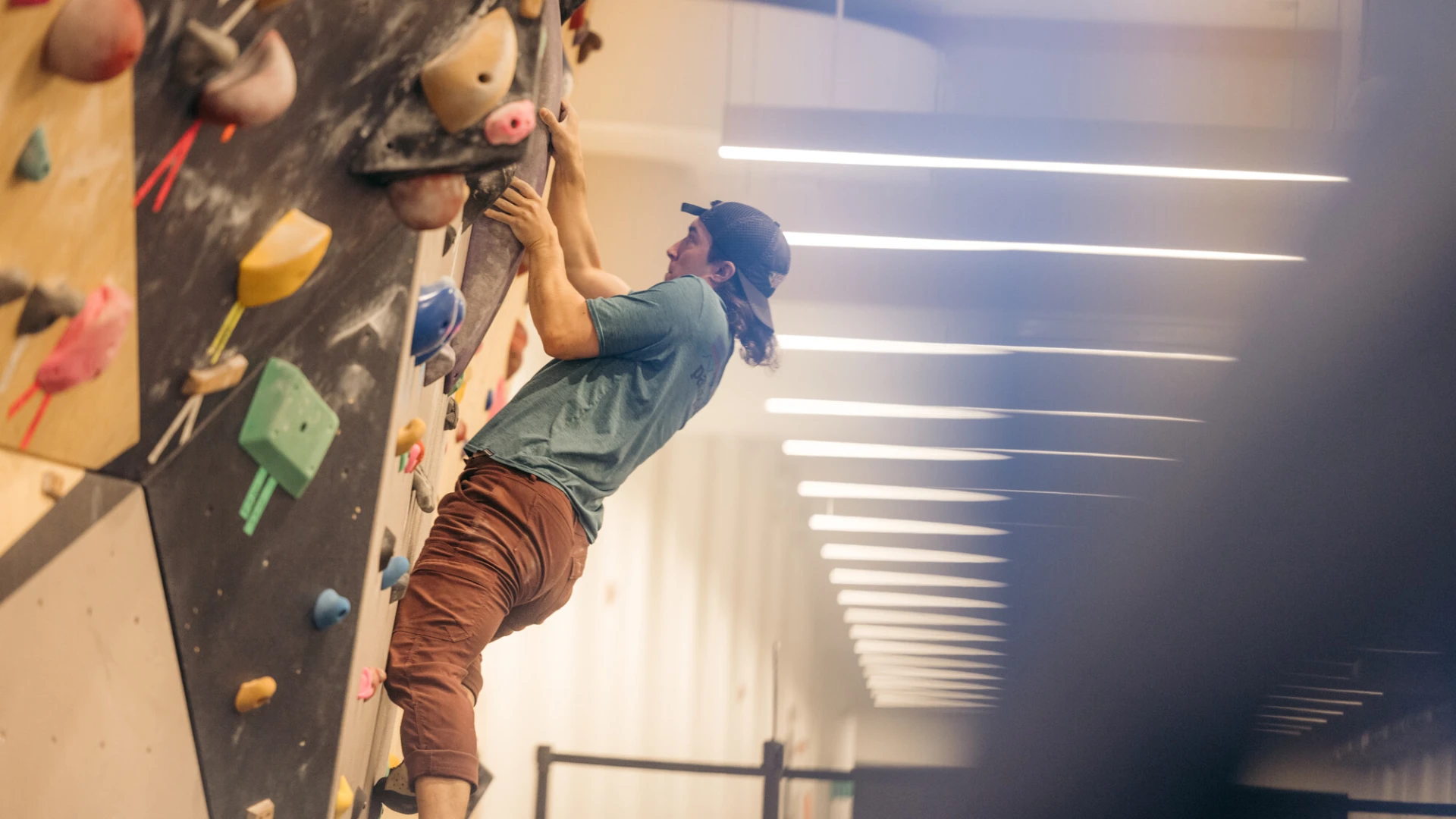 Climber ascends bouldering wall in indoor climbing gym