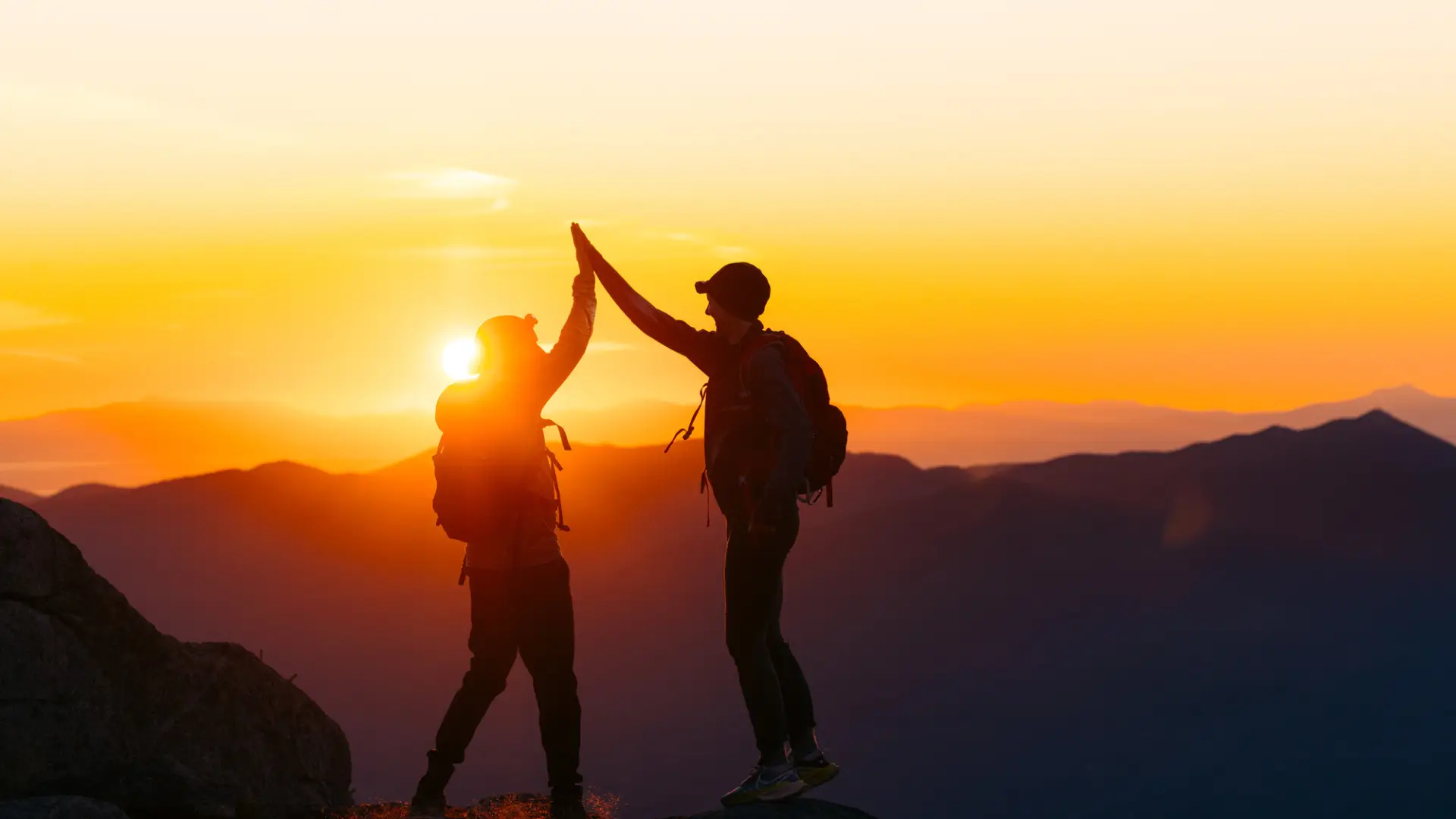 Two people high fiving on a summit