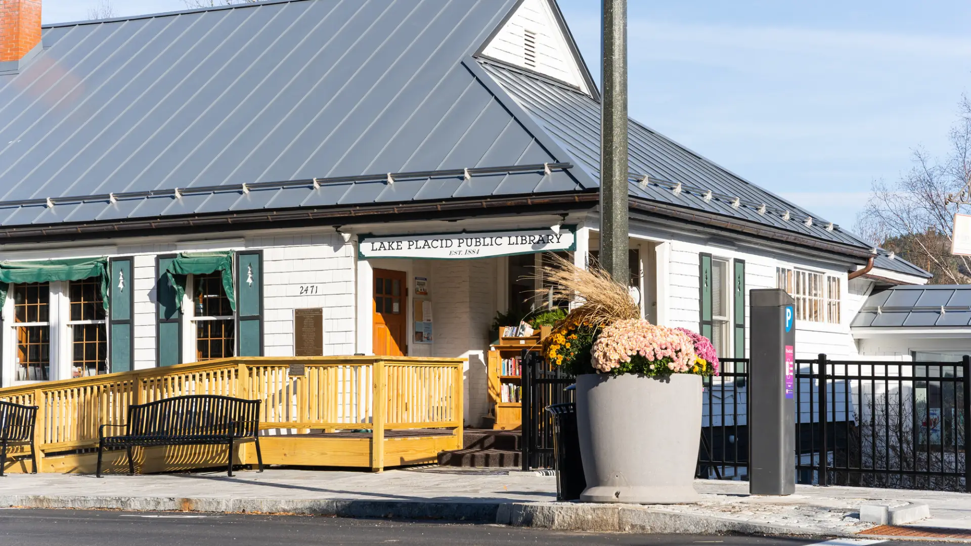Exterior of the public library from the middle of Main Street showing the ramp, bench and community flower pots