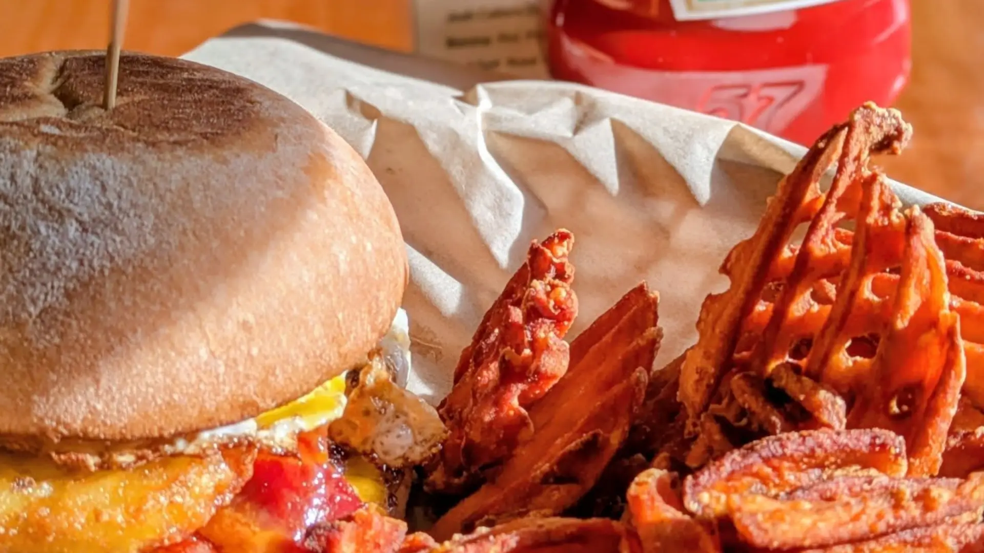 A cheeseburger topped with a fried egg and crispy bacon with golden waffle cut fries.