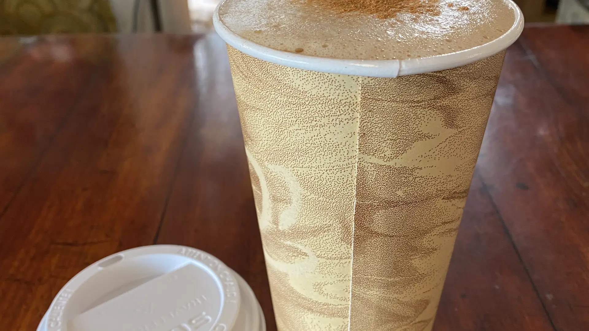 A foamy coffee drink on a wooden counter.