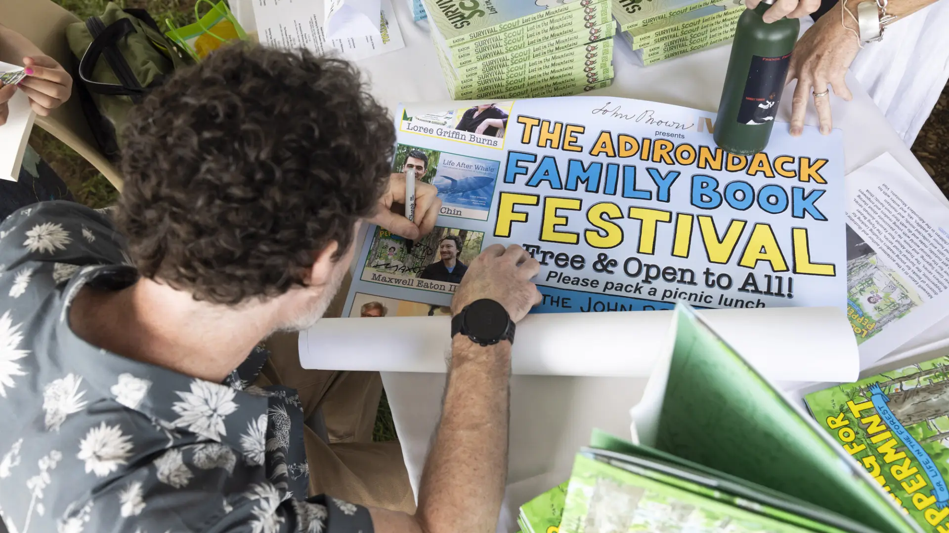 View from above as author signs Adirondack Family Book Festival poster