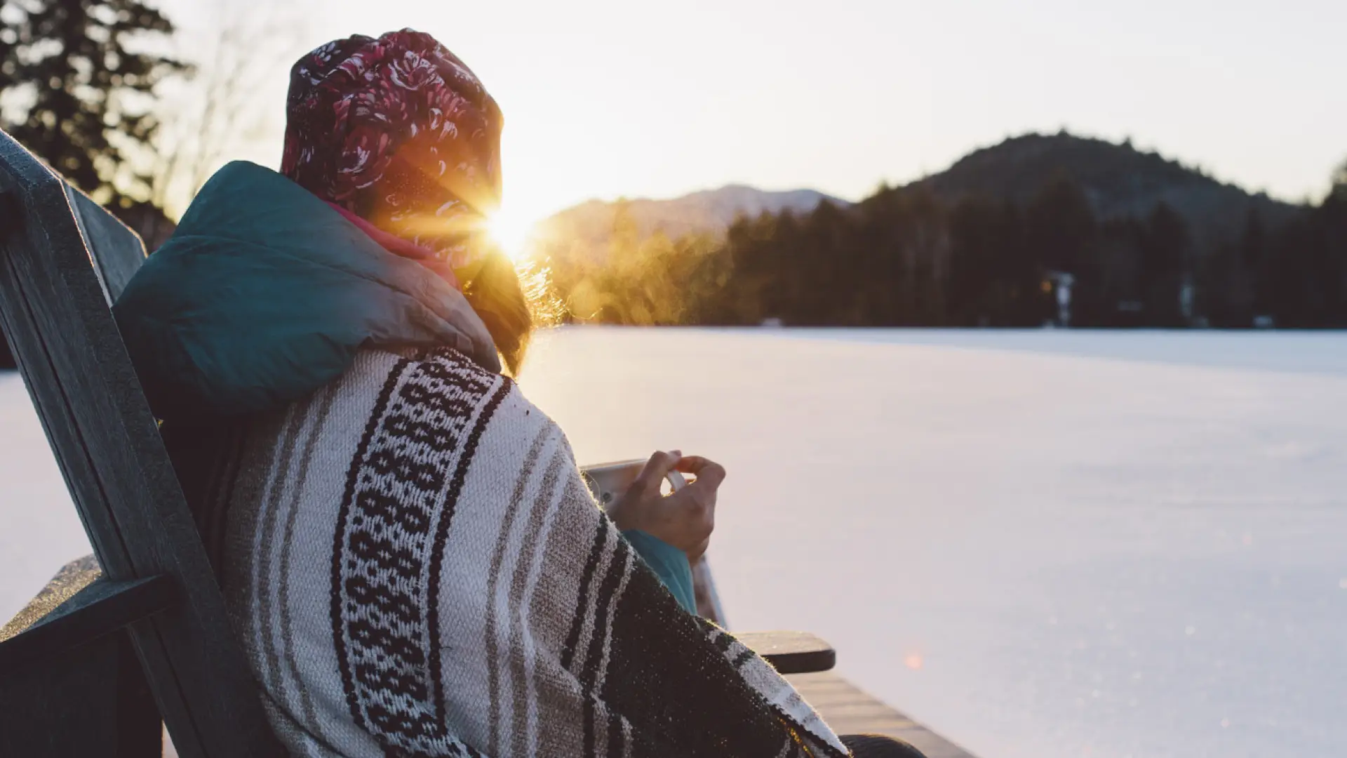 A woman sitting outside looking out onto frozen Mirror Lake in Lake Placid.