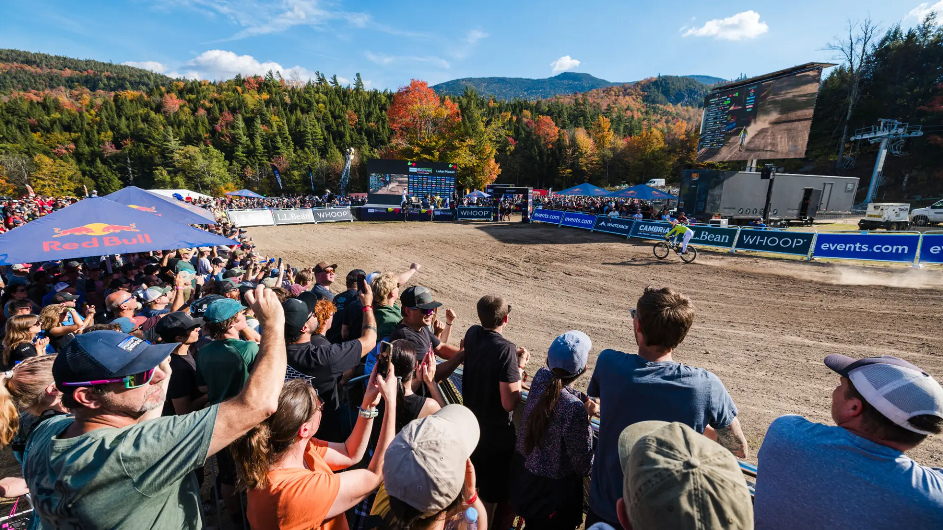 Crowd looks on as downhill mountain bike races enter finish line corral at Whiteface during UCI MTB Downhill World Cup race
