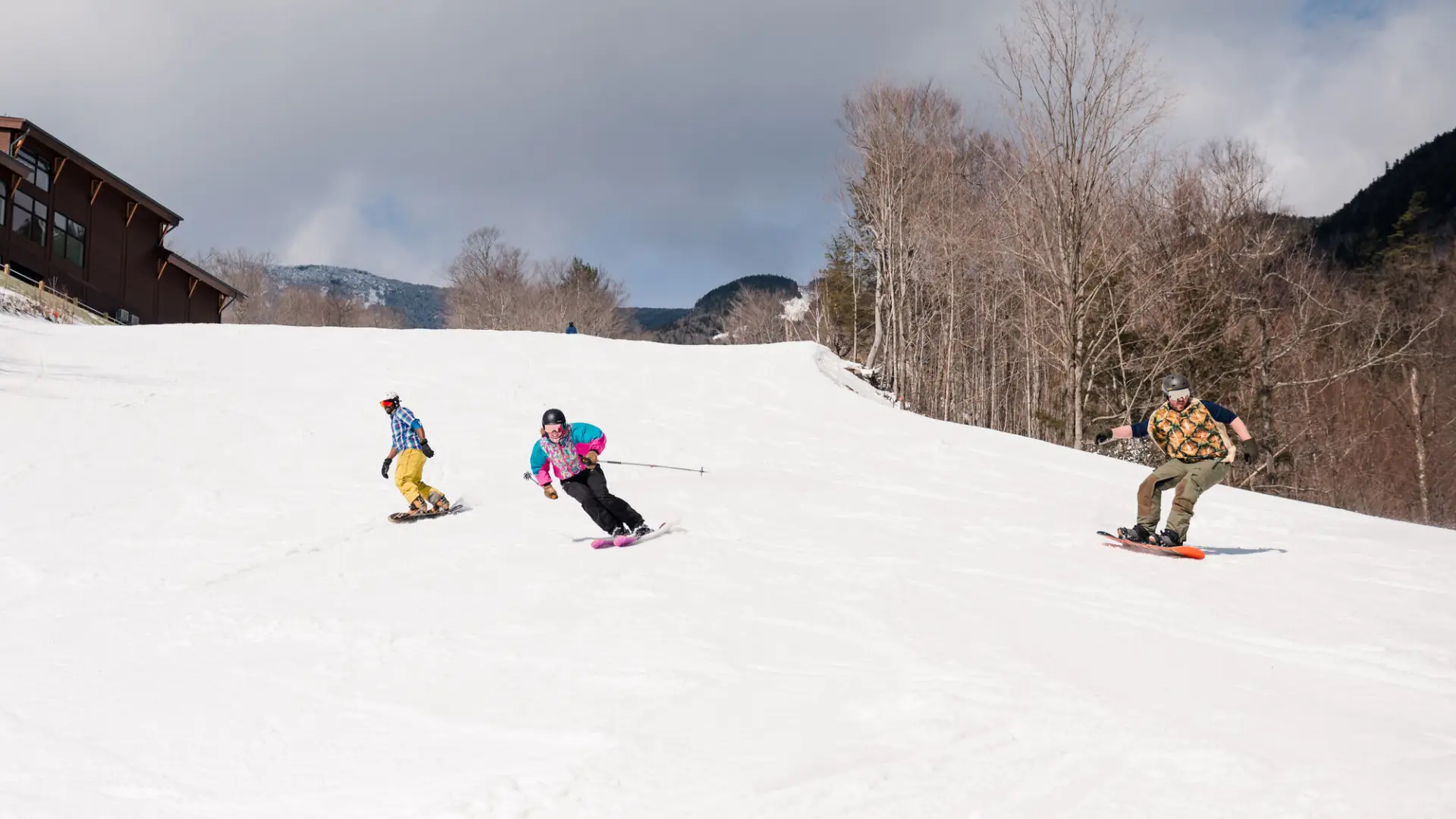 Skiers and boarders carve their way down a snowy slope.