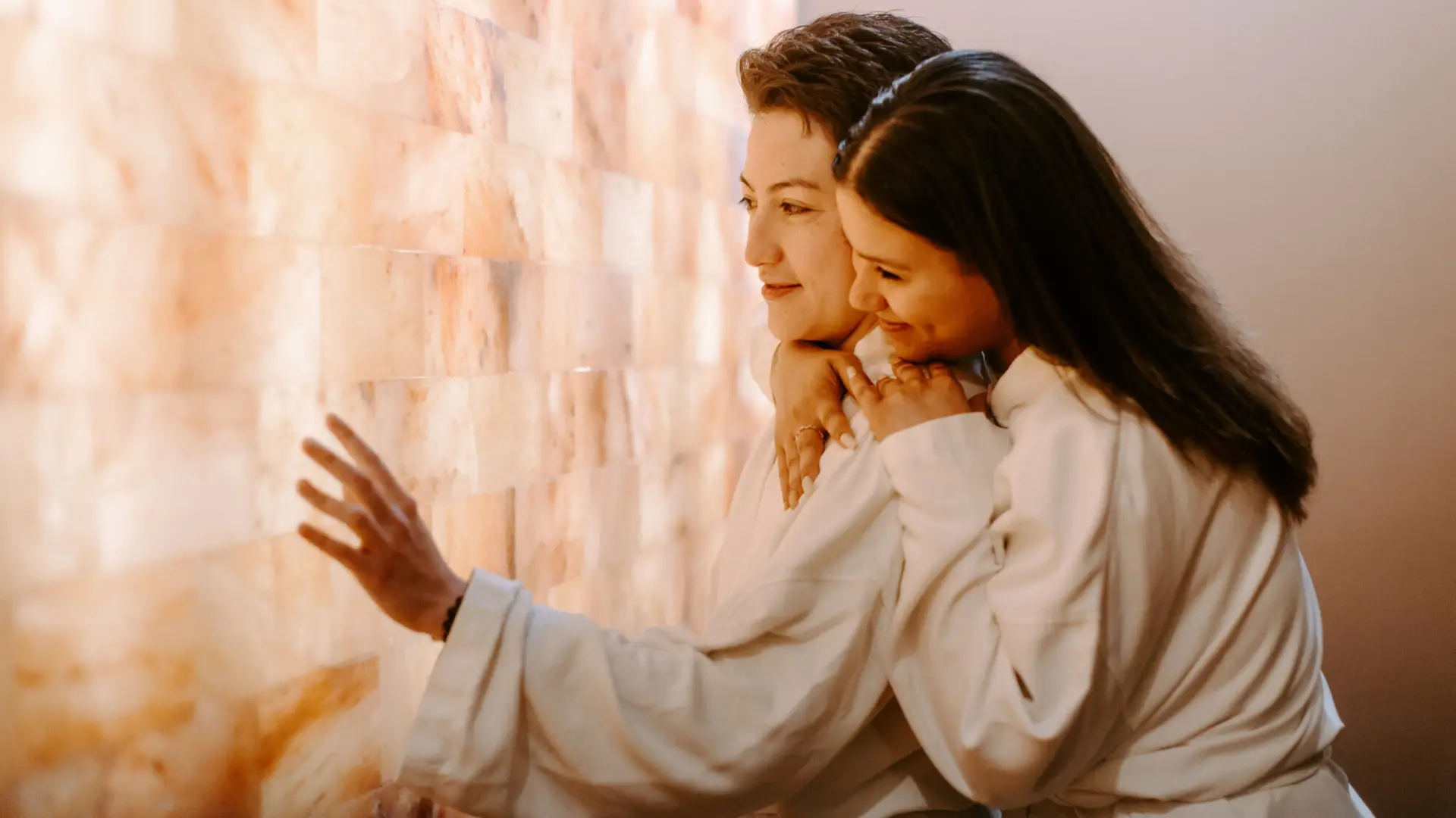 Two women hug in a spa salt room.