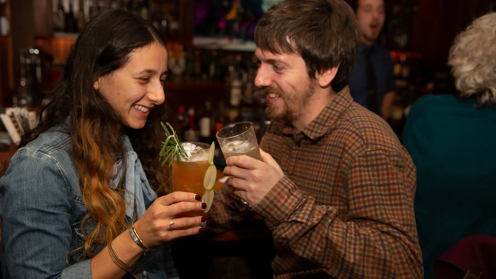 A couple holds cocktails at a bar.