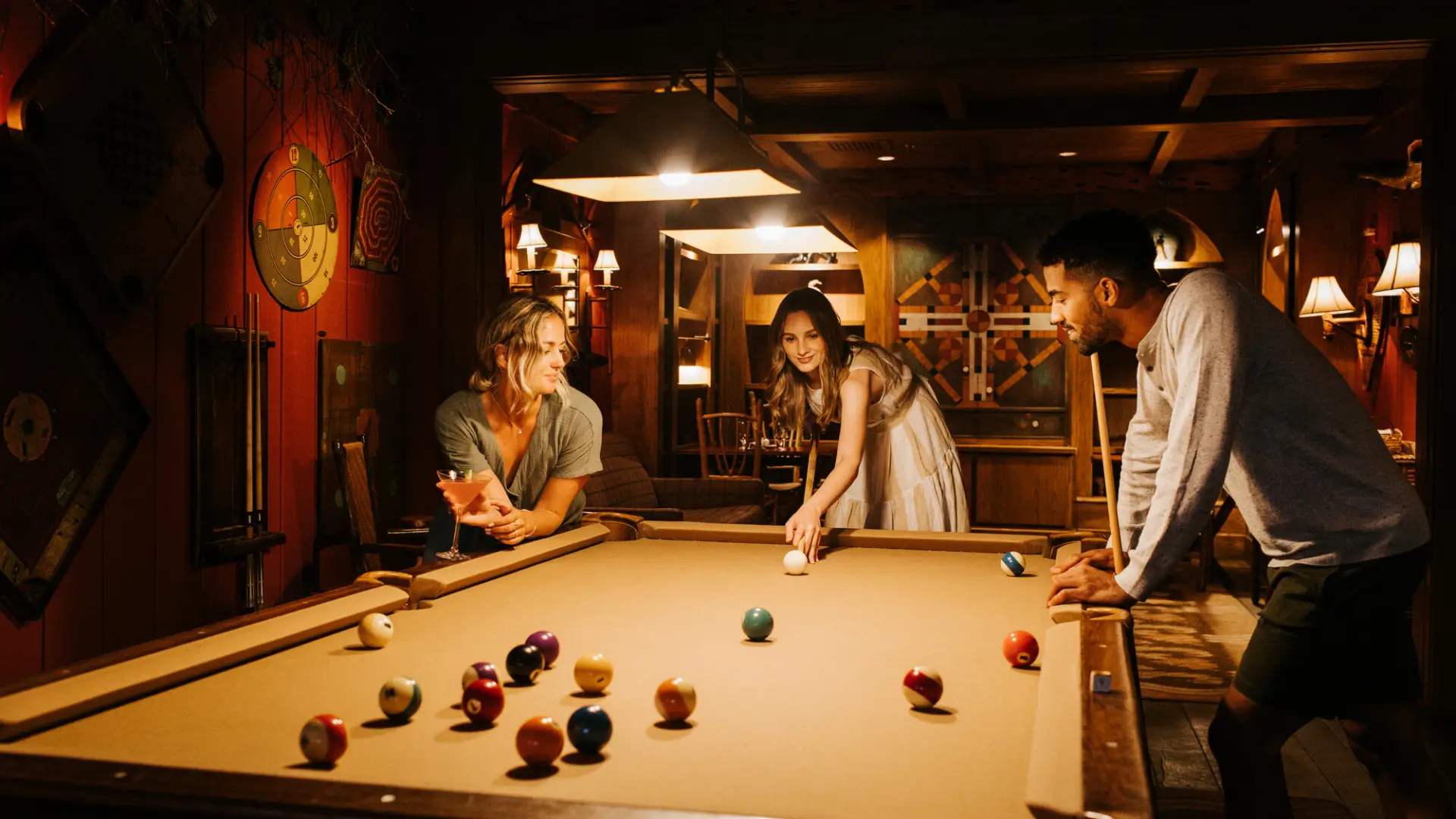 Three friends play pool in a lodge.