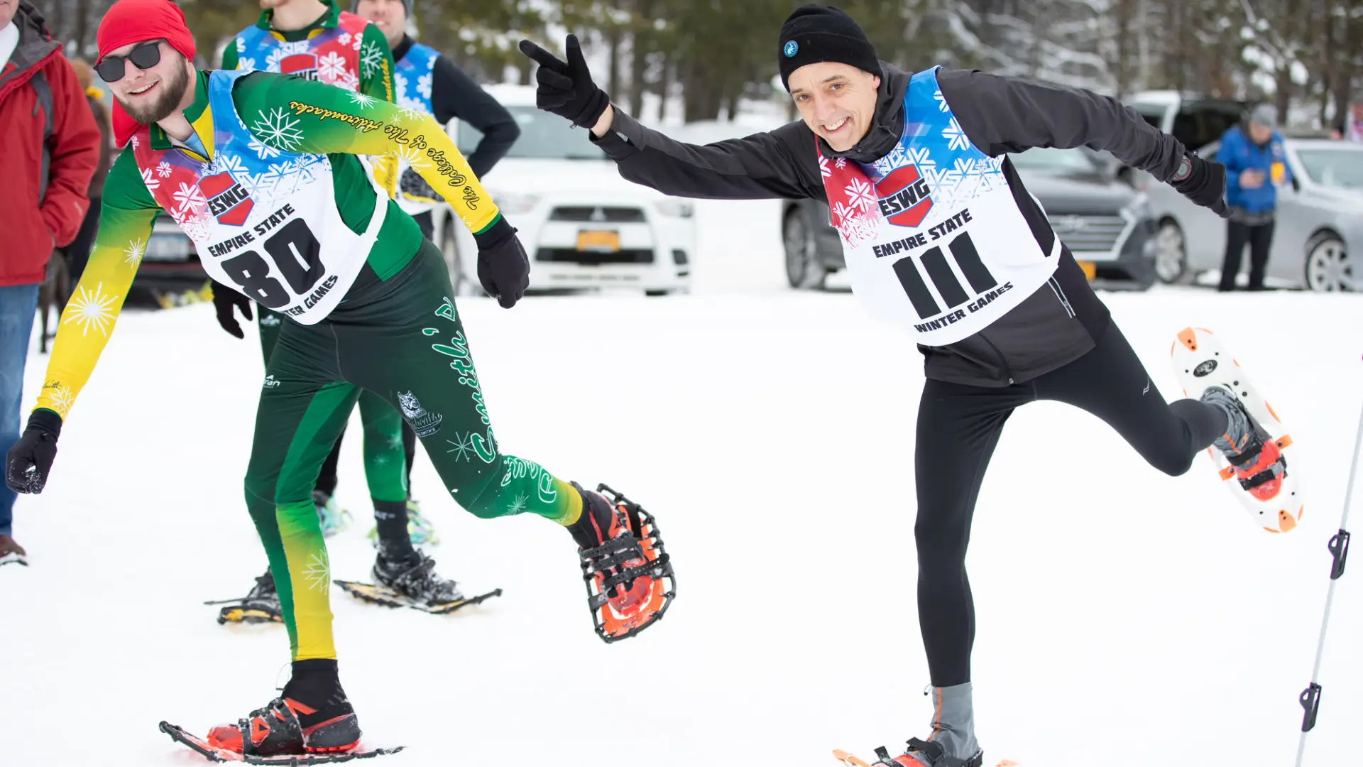 Two men in snowshoes race in colorful winter gear.