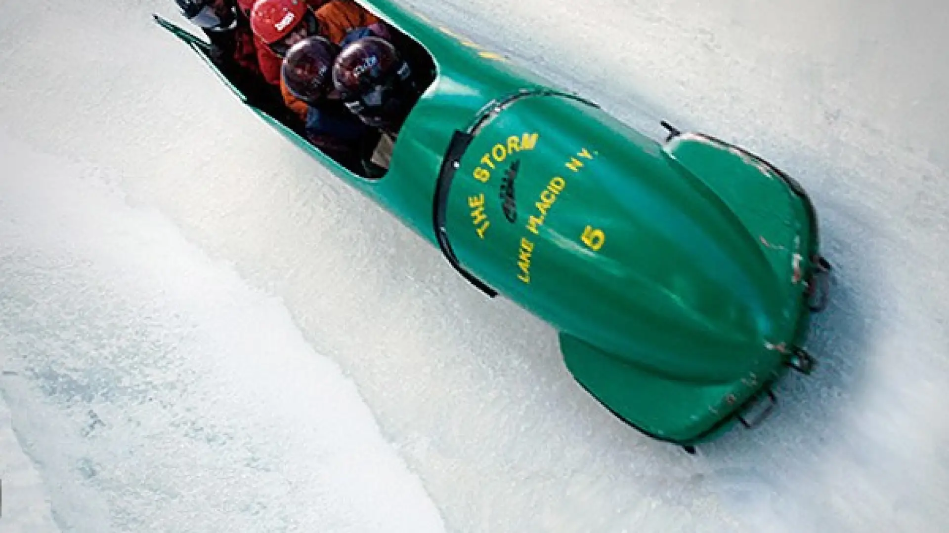 A group of five riding a green bobsled on an icy track.