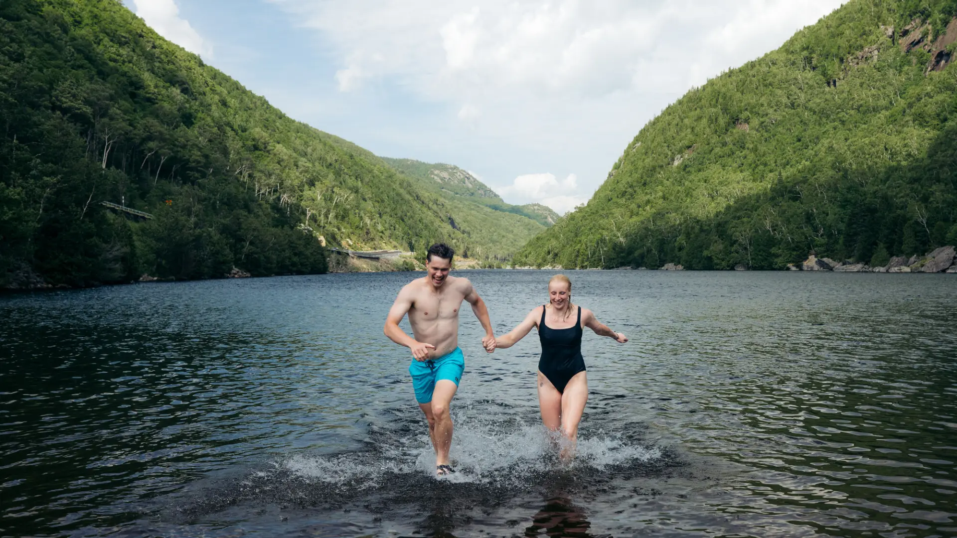 A man and woman run out of a lake. 