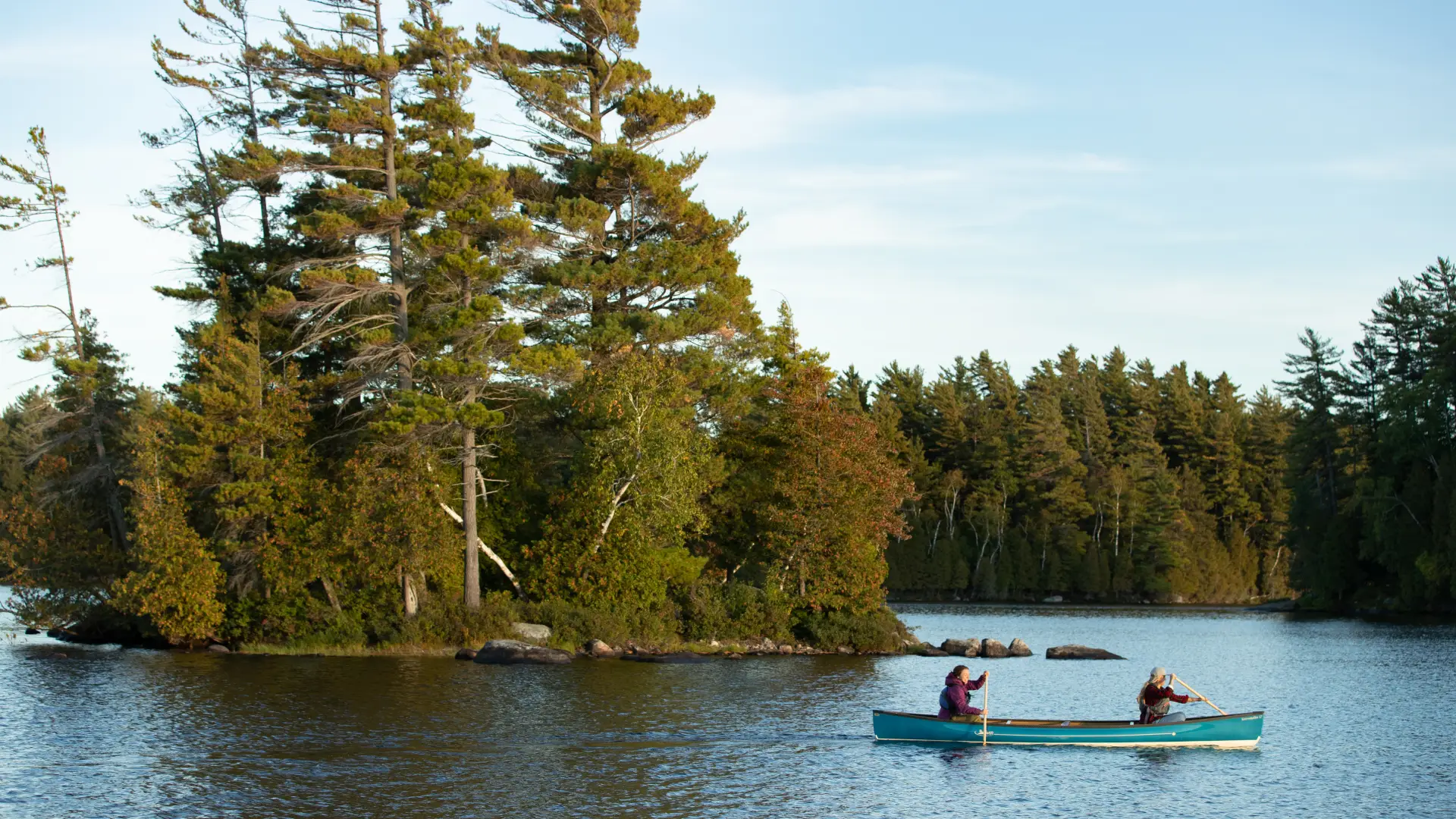 Two paddlers passing one of the smaller Saranac islands in a canoe.