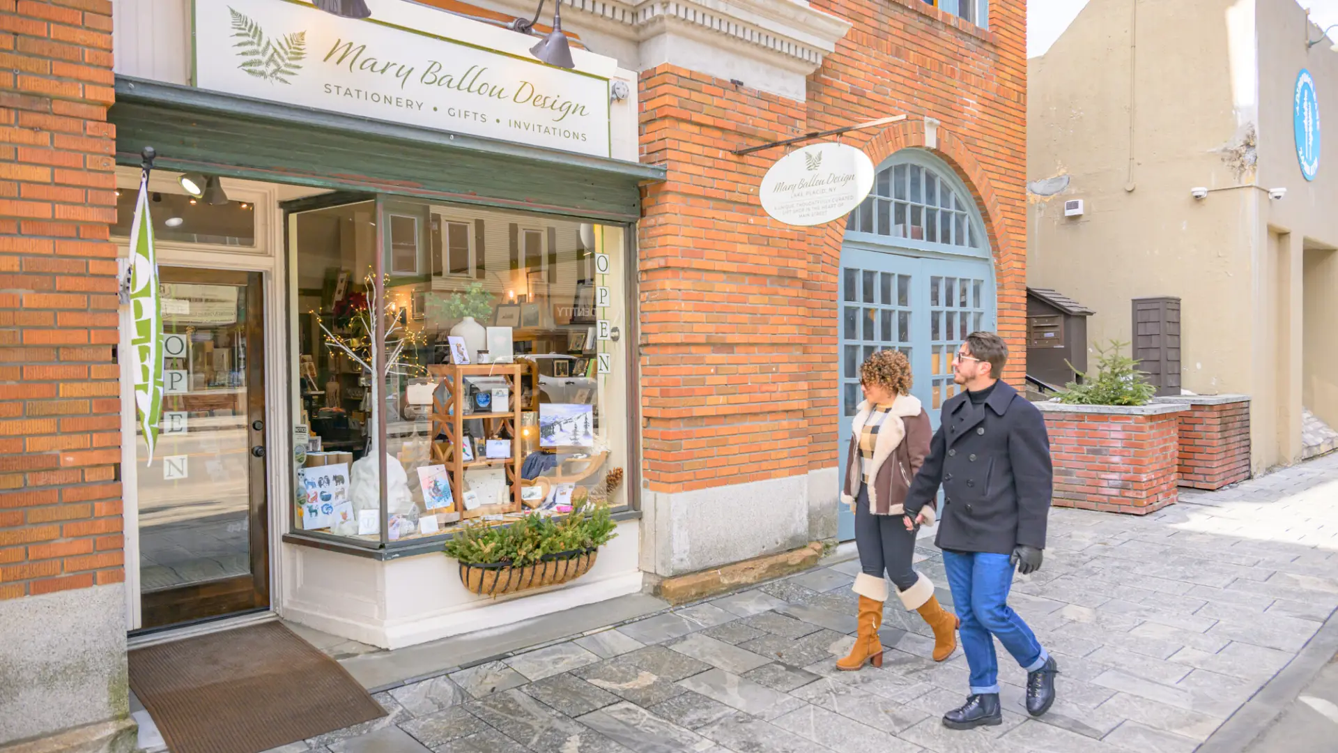 Couple walks hand in hand past shop on Main St. Lake Placid