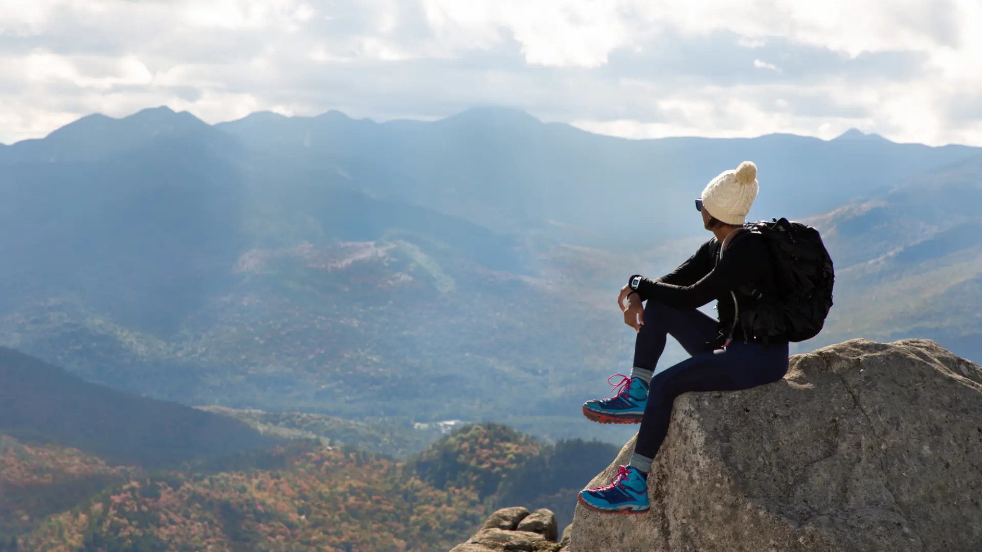 A person at the summit of a hike in Keene during summer.