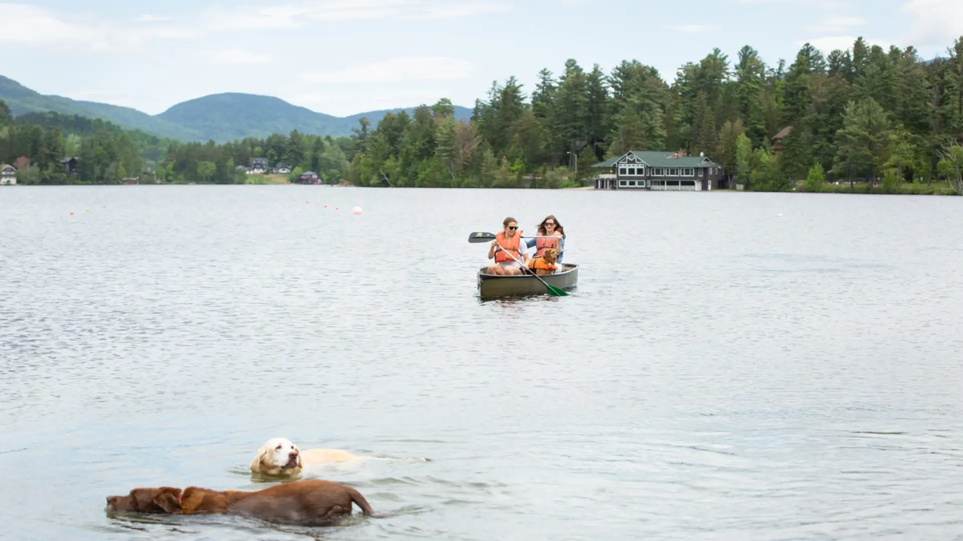 People canoe in a tandem green boat on the lake.