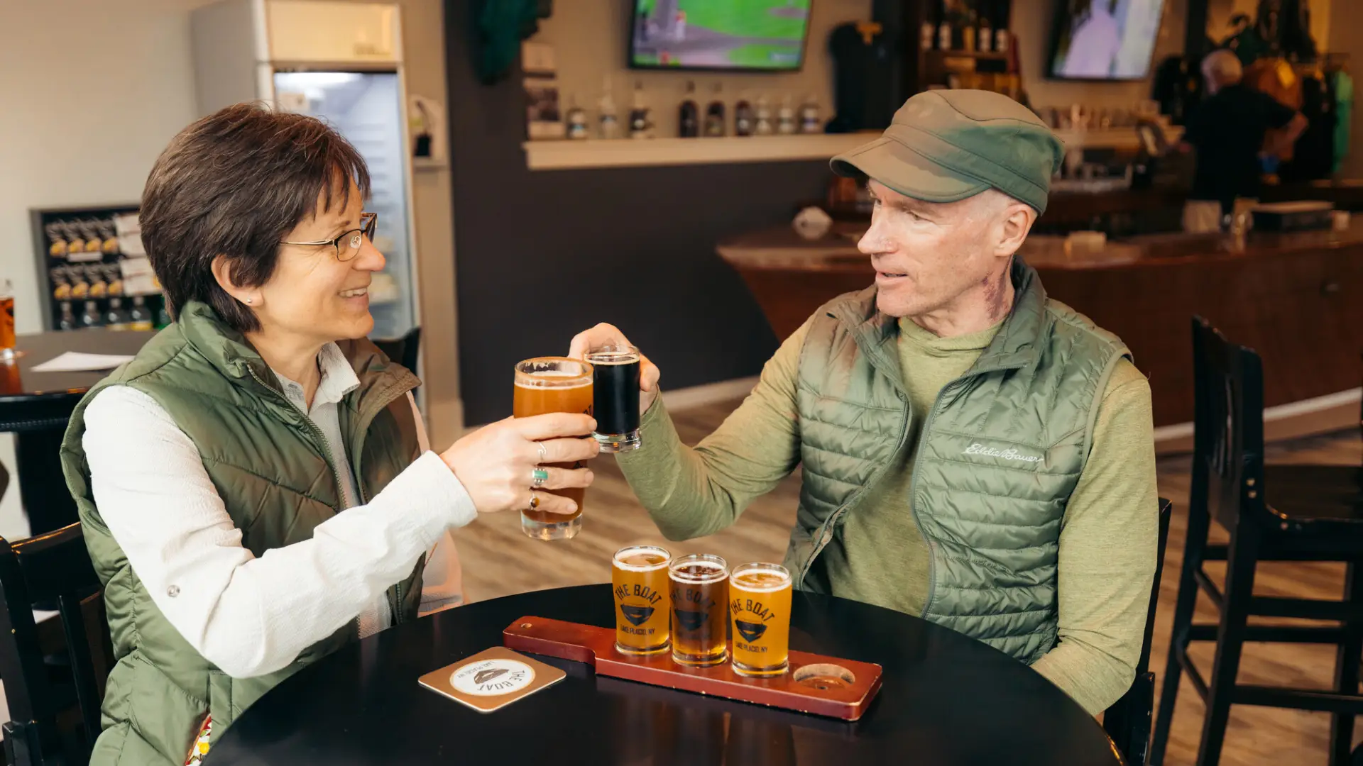 A man and woman share a flight of beers at a brewery.