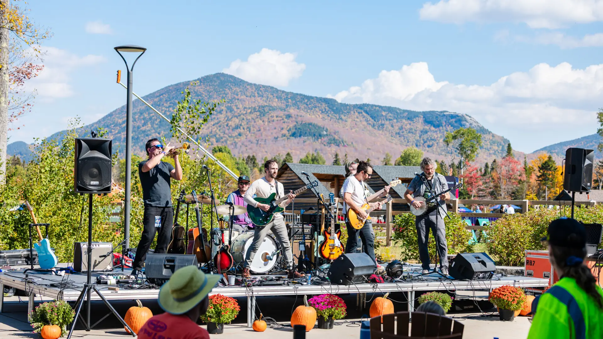 Band plays live music on stage decorated with pumpkins and mums with mountain in background