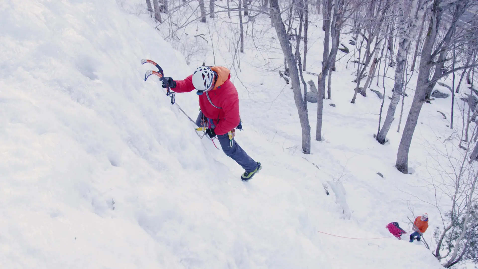 Man ice climbing with his belayer far below