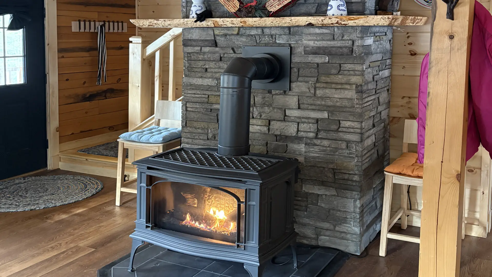 A fire burning in the wood stove in the stacked stone fireplace.