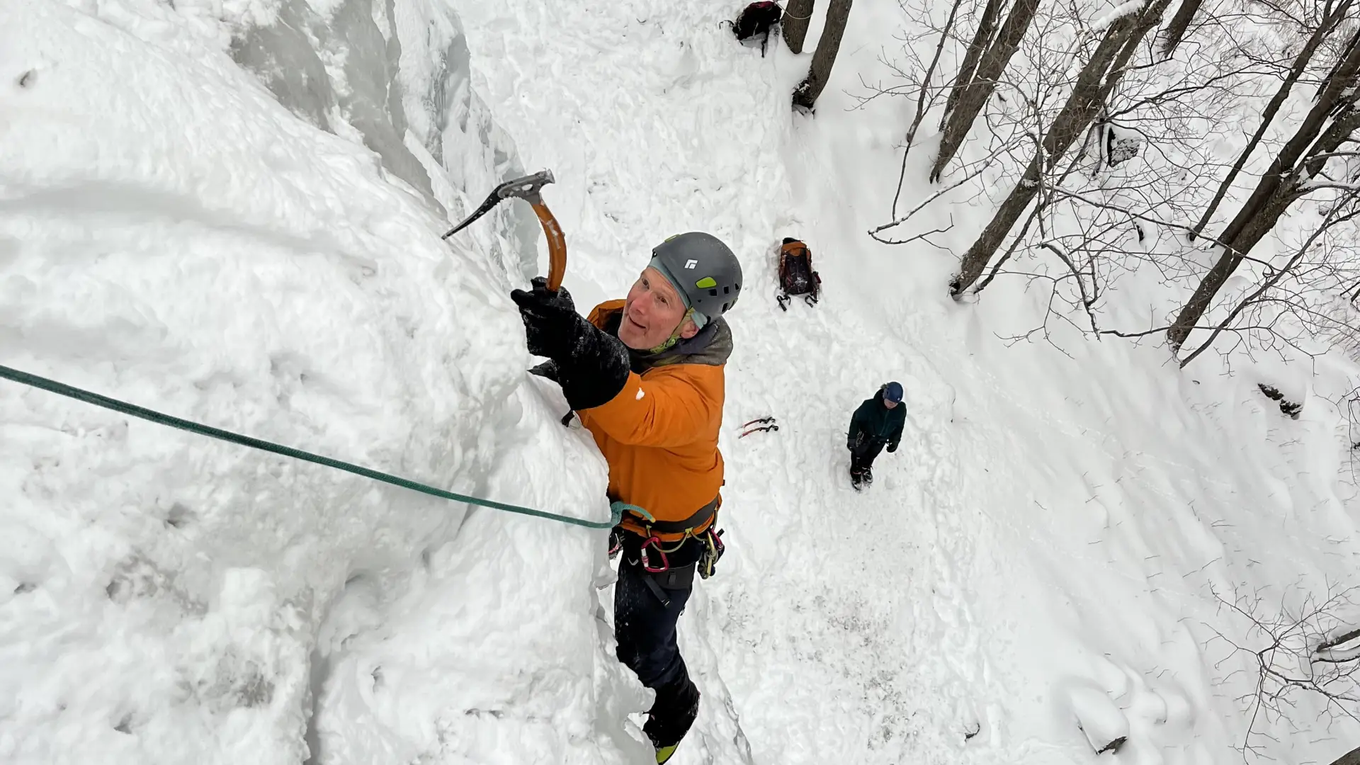 Man with an ice pick ascends an ice wall
