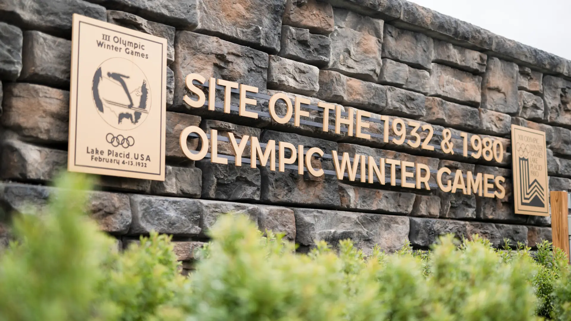 A stone and metal sign signifying the site of the 1932 and 1980 Winter Olympic Games