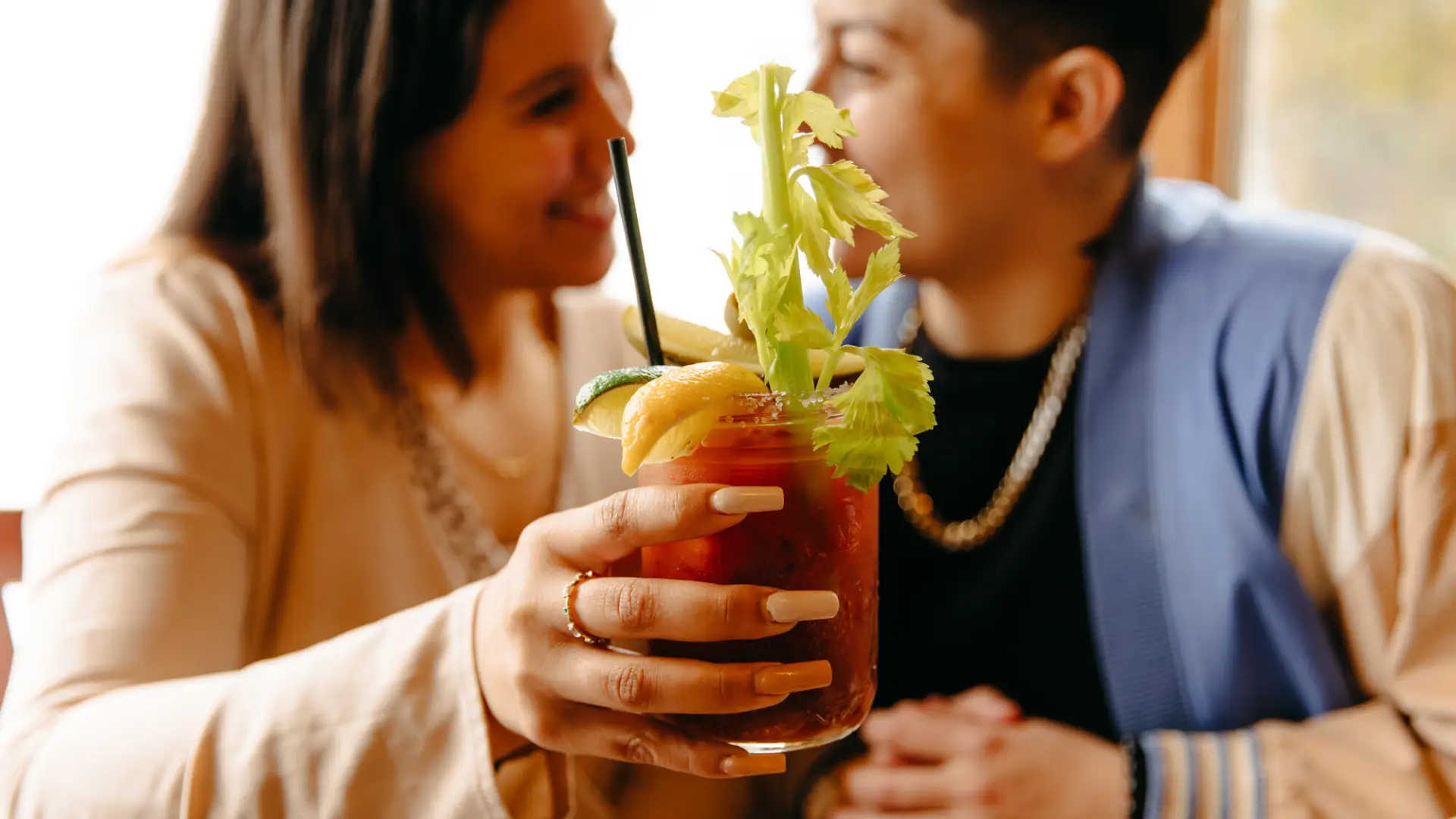 Couple holding up bloody mary in a jar