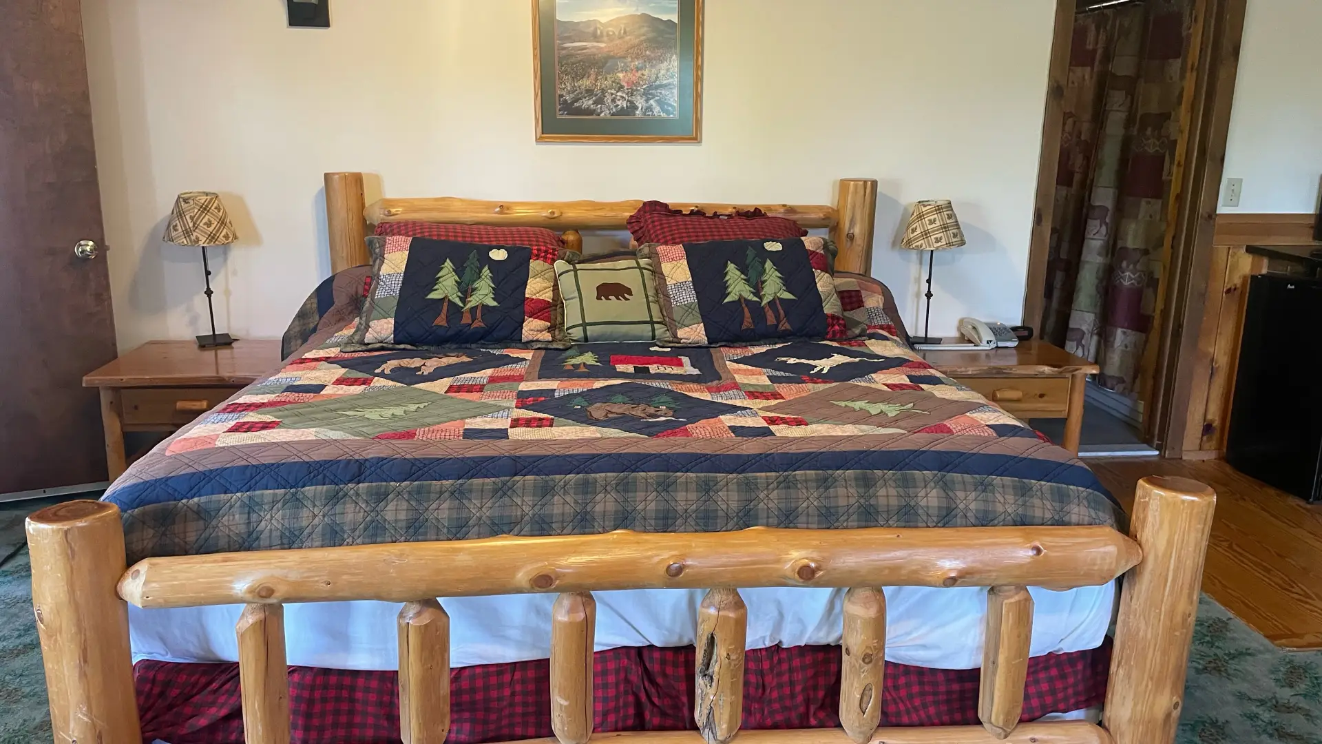 A king sized log bed with colorful quilts at Wildwood on the Lake.