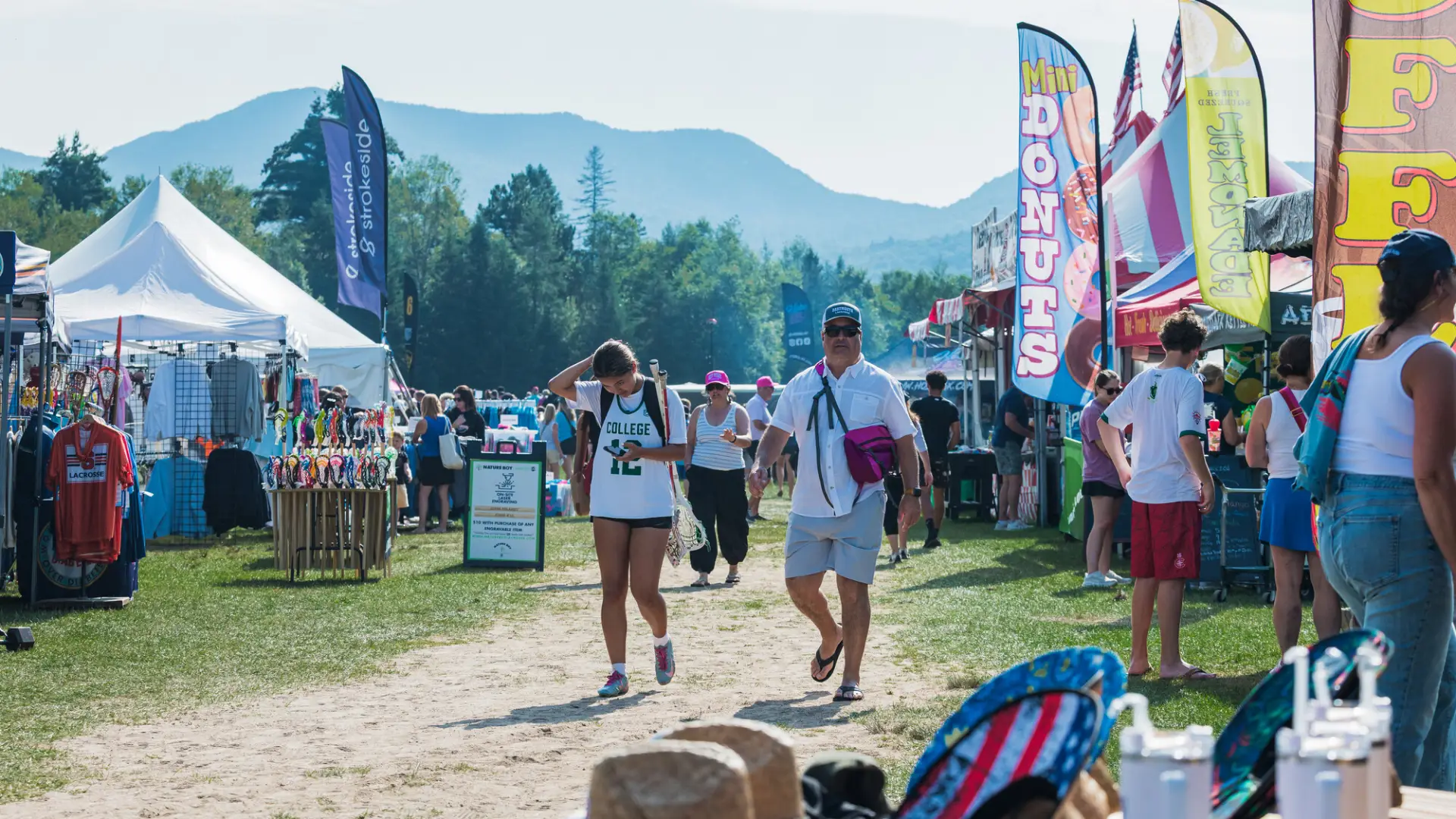 People walk down roadway flanked by vendors at Lacrosse tournament in Lake Placid