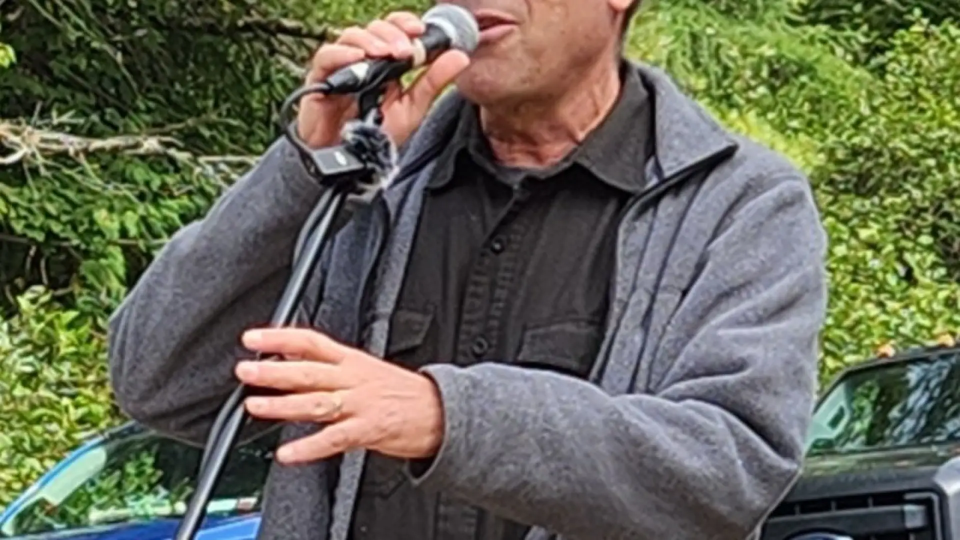 Curt Stager speaks into a microphone wearing a grey jacket and baseball cap
