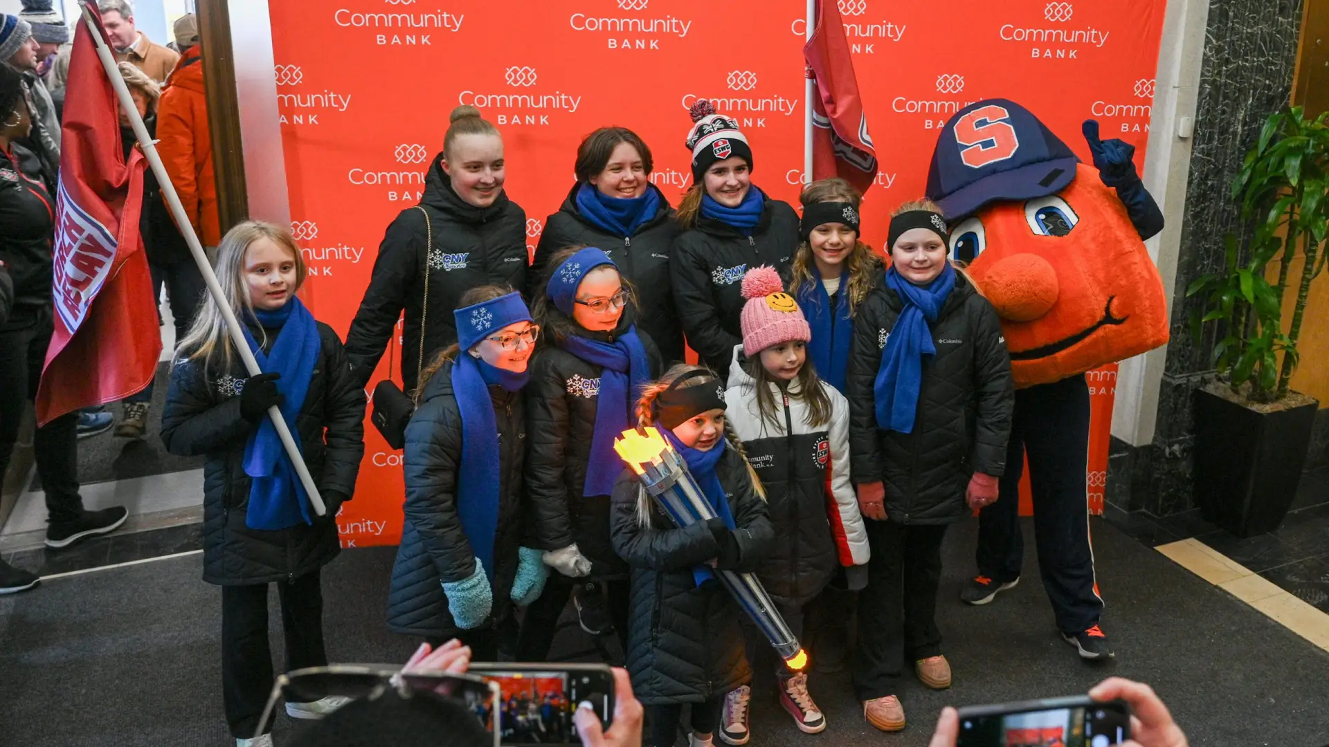 A group of children in winter coats and blue scarves, holding a torch during the Empire State Winter Games Torch Relay.