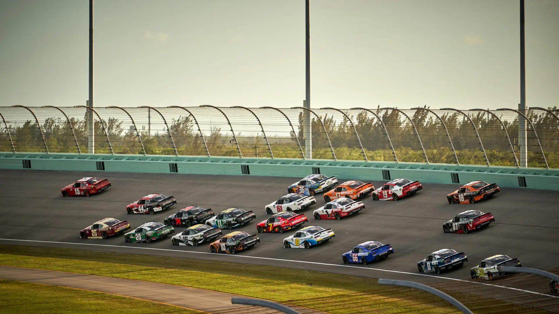 Nascar vehicles race around a paved track