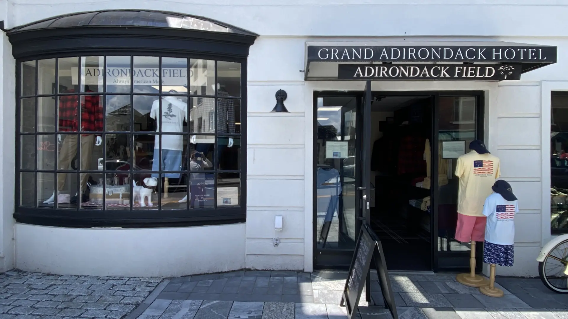 The entry of the white building with black trim and awning for Adirondack Field.