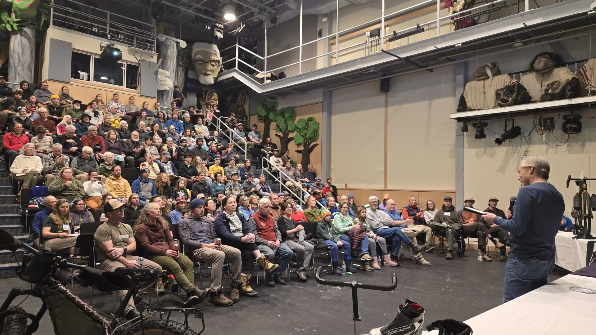 Glenn Glover, Executive Director of BETA, speaks in front of full theater at North Country School
