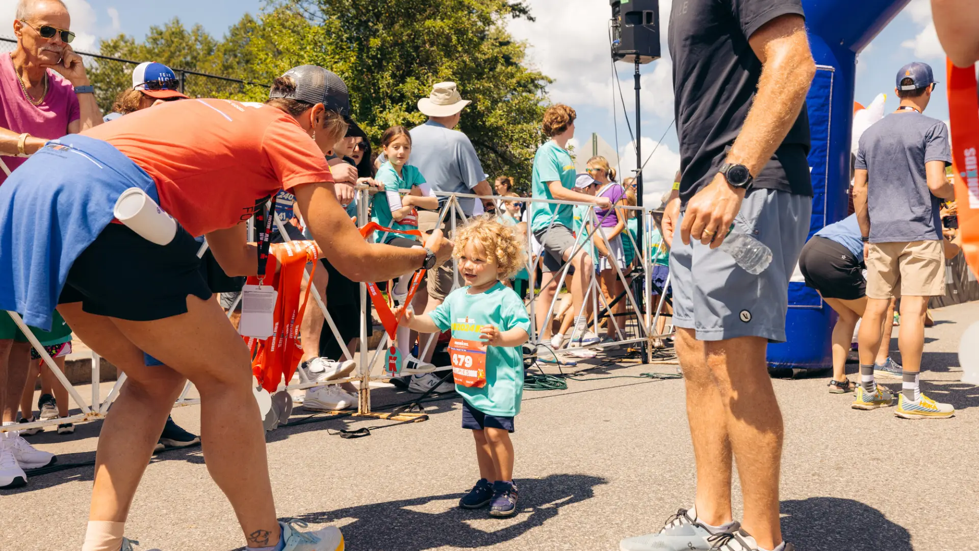 Race worker hands medal to small smiling child at finish line of Lake Placid Ironkids race