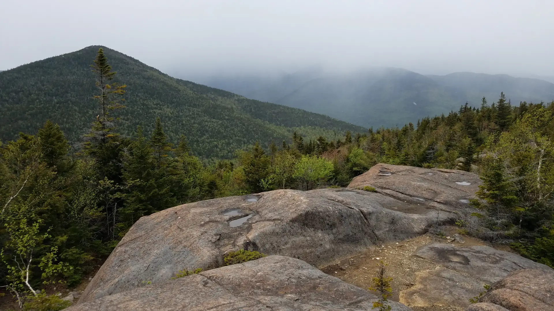 The view of a pointed mountain from a bare rock summit