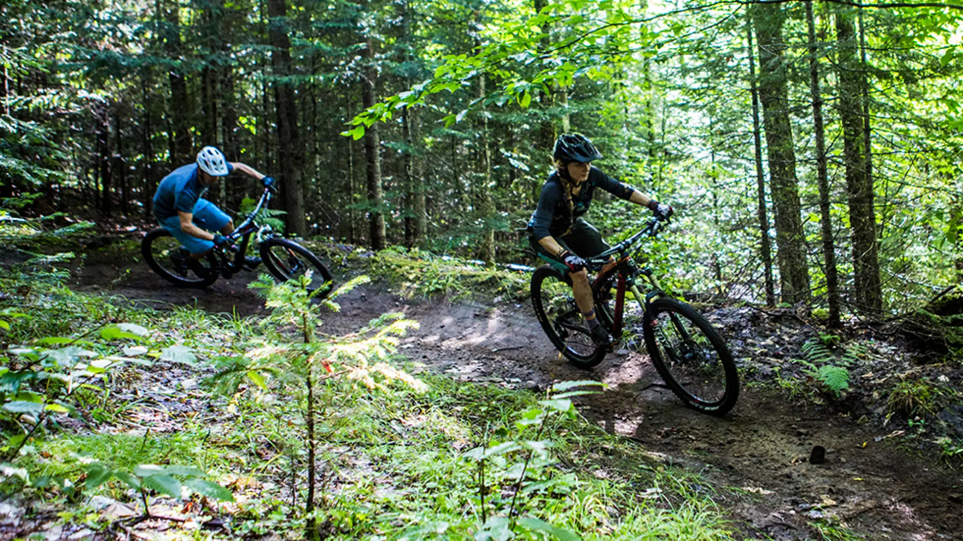 A pair of riders hug a turn on a mountain bike trail