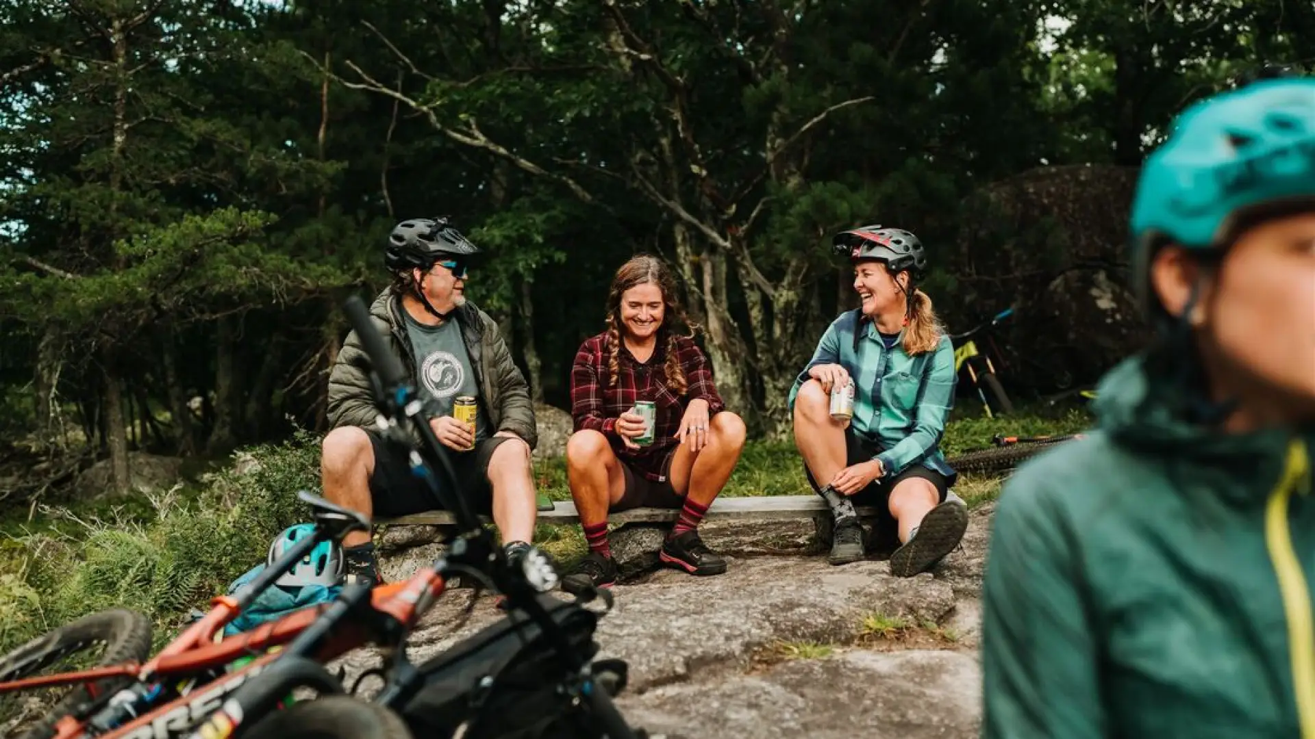 Group of bikers sitting on rock wearing bike gear with bikes laying down nearby