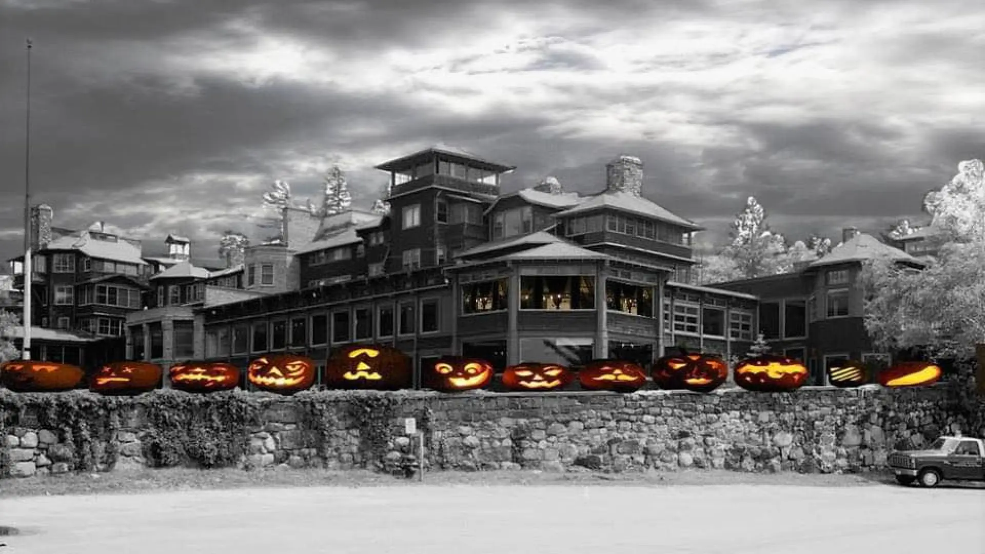 A black and white image of an old Adirondack hotel, photoshopped with spooky cartoon pumpkins