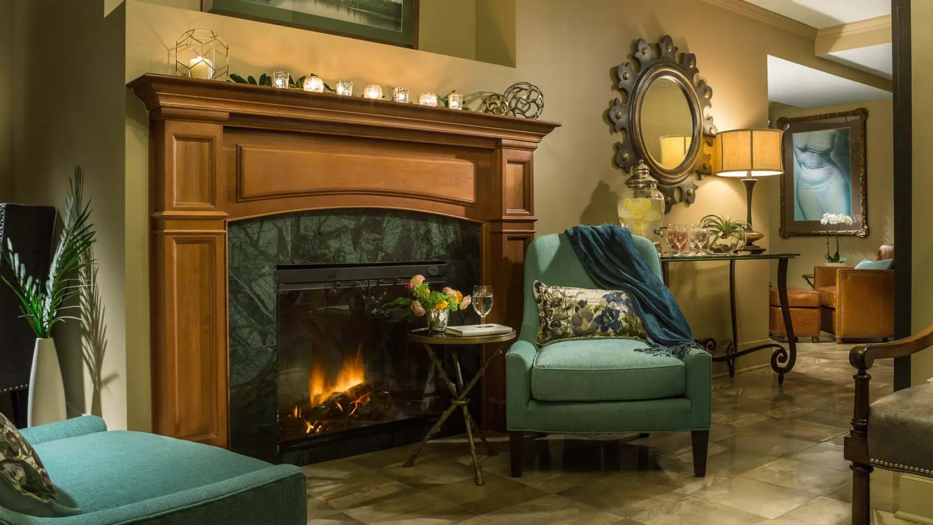 The luxurious women's lounge decorated with a robust fireplace, comfortable chairs, and candle light.