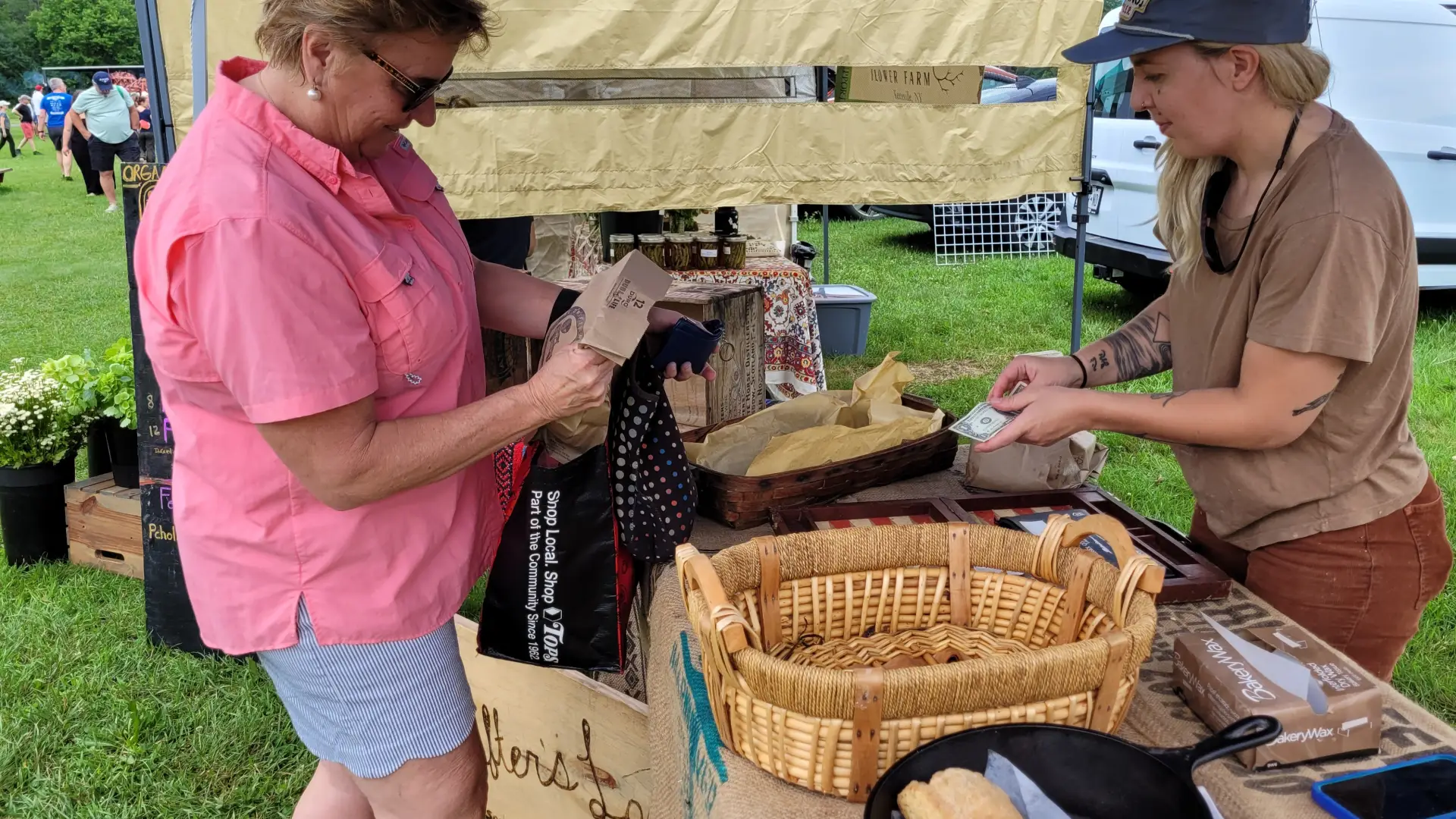 A woman buys a loaf of bread from Courtney Marvin at The Drifters Loaf, located at the Keene Farmers Market