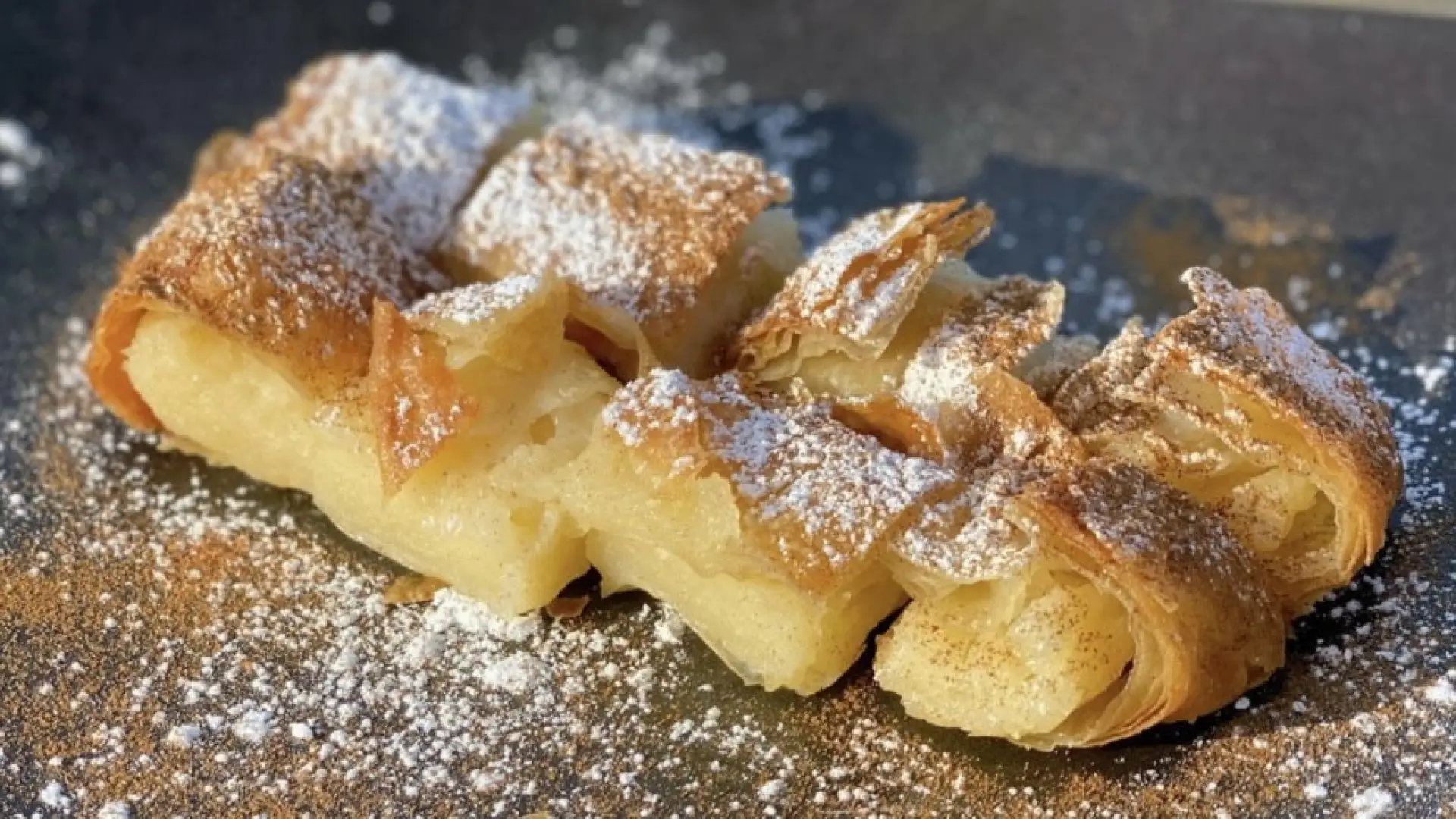 Bougatsa: 
Custard Cream filling that wrapped with thin layered pastry of filo dough, topped with sugar powdered and cinnamon powder. Freshly baked, served warm but it also enjoyable when its chilled.