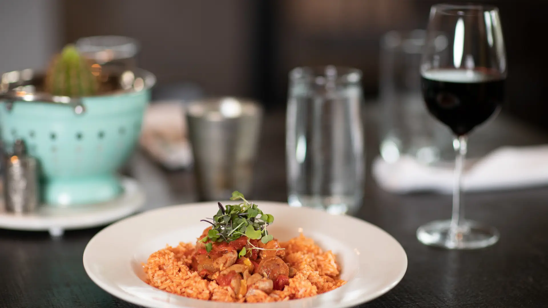 A plate of rice and jambalaya and glass of wine on a modern dining table.