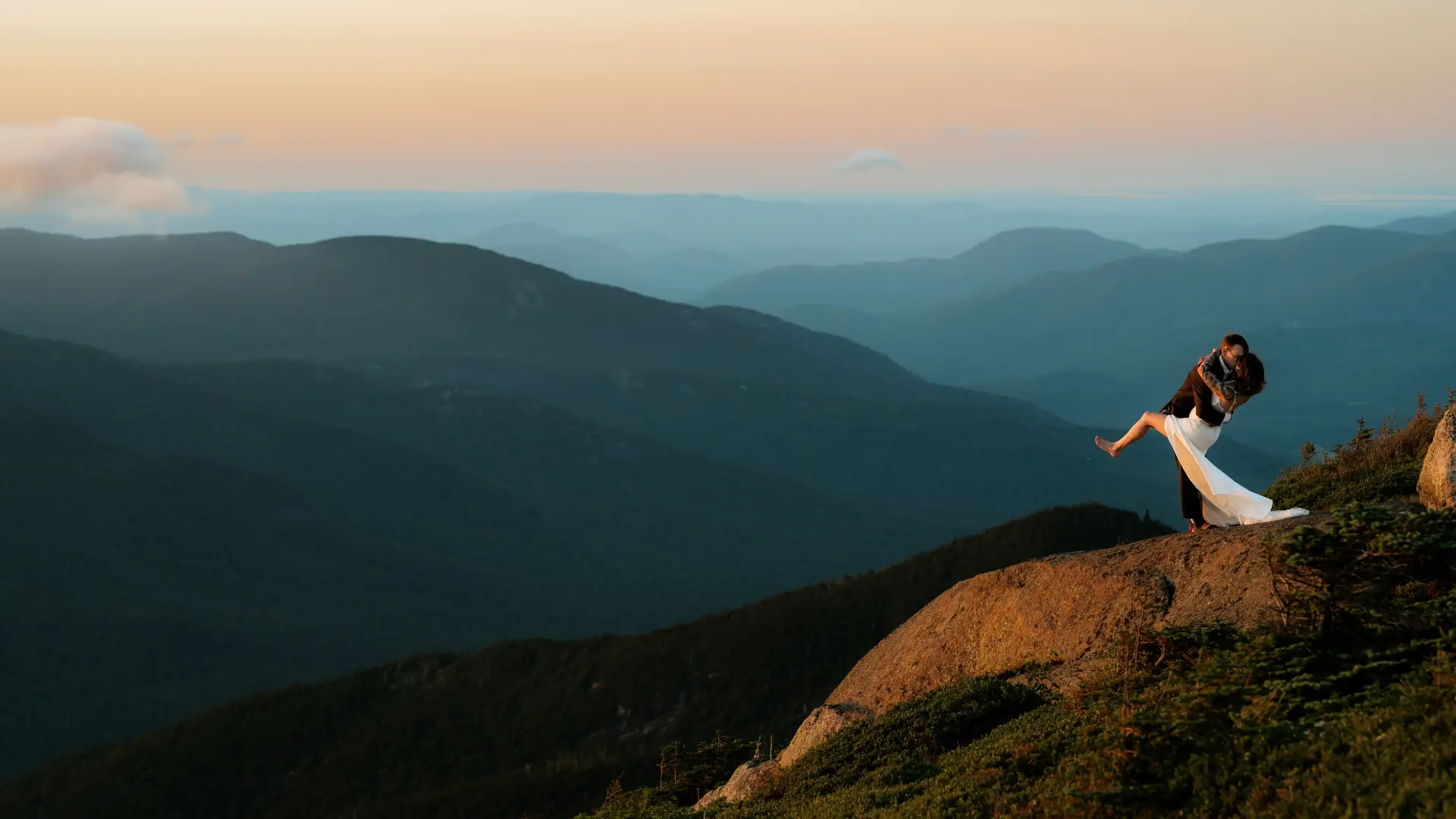 A dip and a kiss of bride and groom on top of a mountain