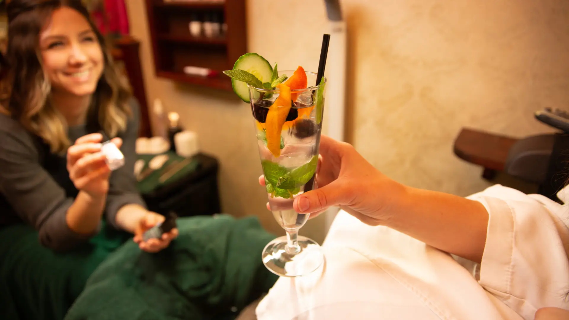 A woman's hand holds a mineral water adorned with a fresh citrus wedge in a Lake Placid spa