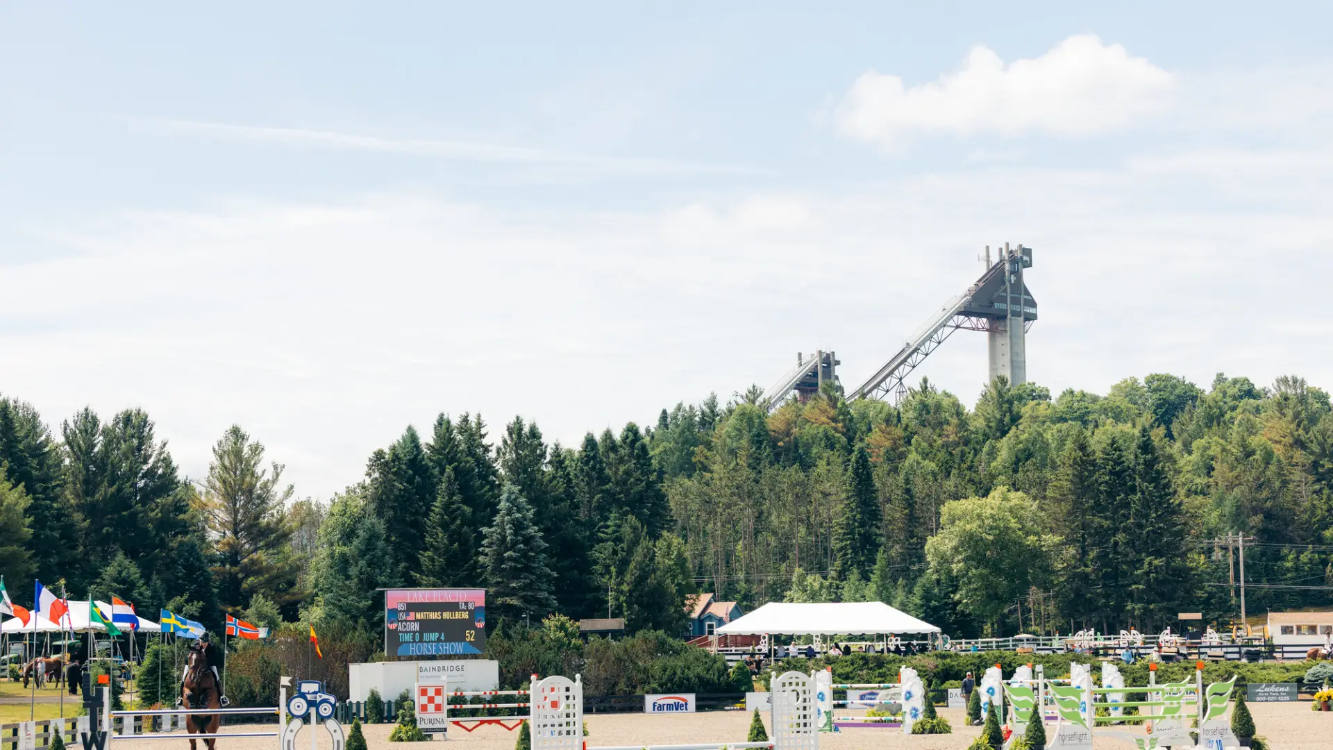 View of Lake Placid Horse Show Grounds during annual horse show with courses set up and ski jumps in the background